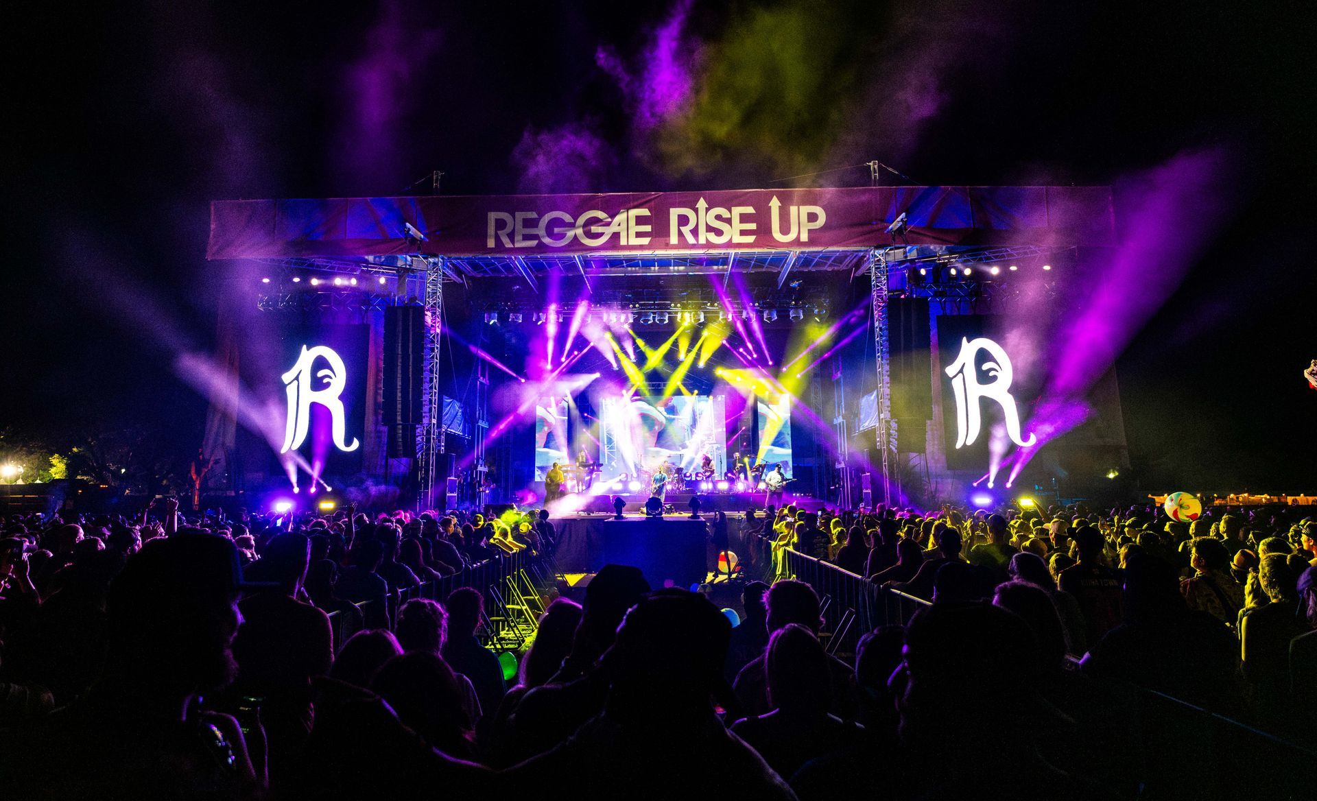 A crowd of people are sitting in front of a stage at a concert.
