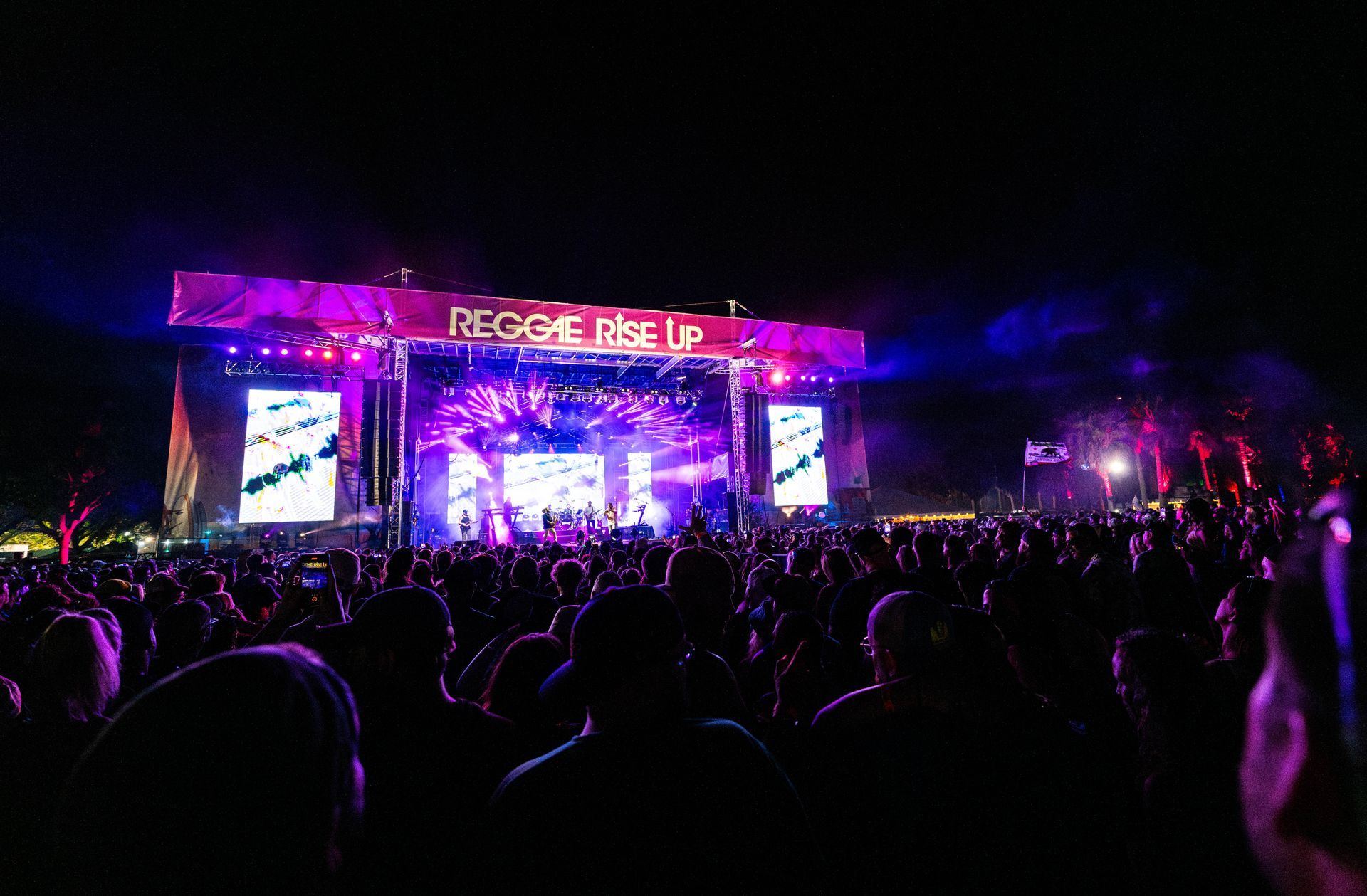 A crowd of people are sitting in front of a stage at a concert.