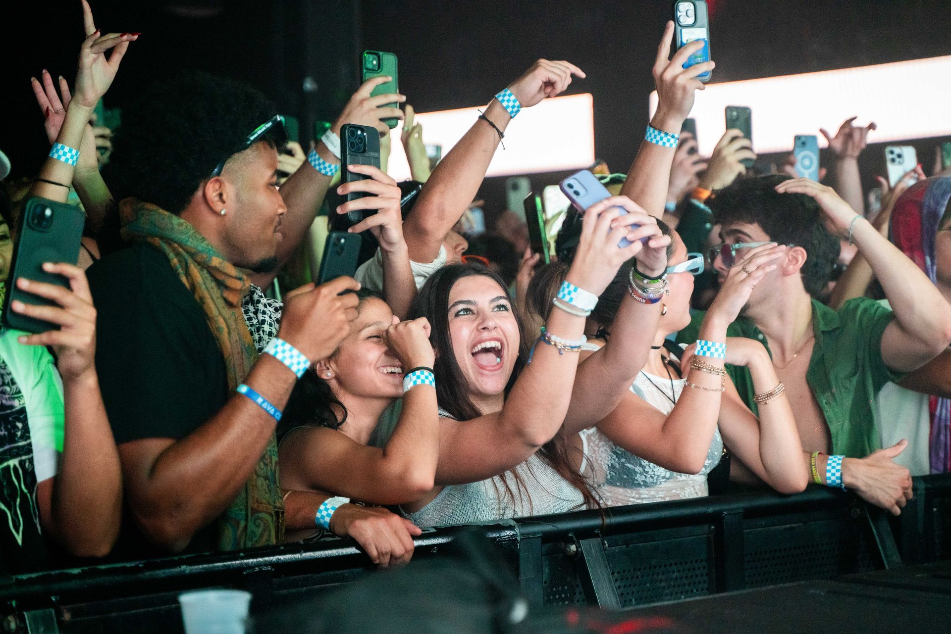 A crowd of people are holding their phones up in the air at a concert.