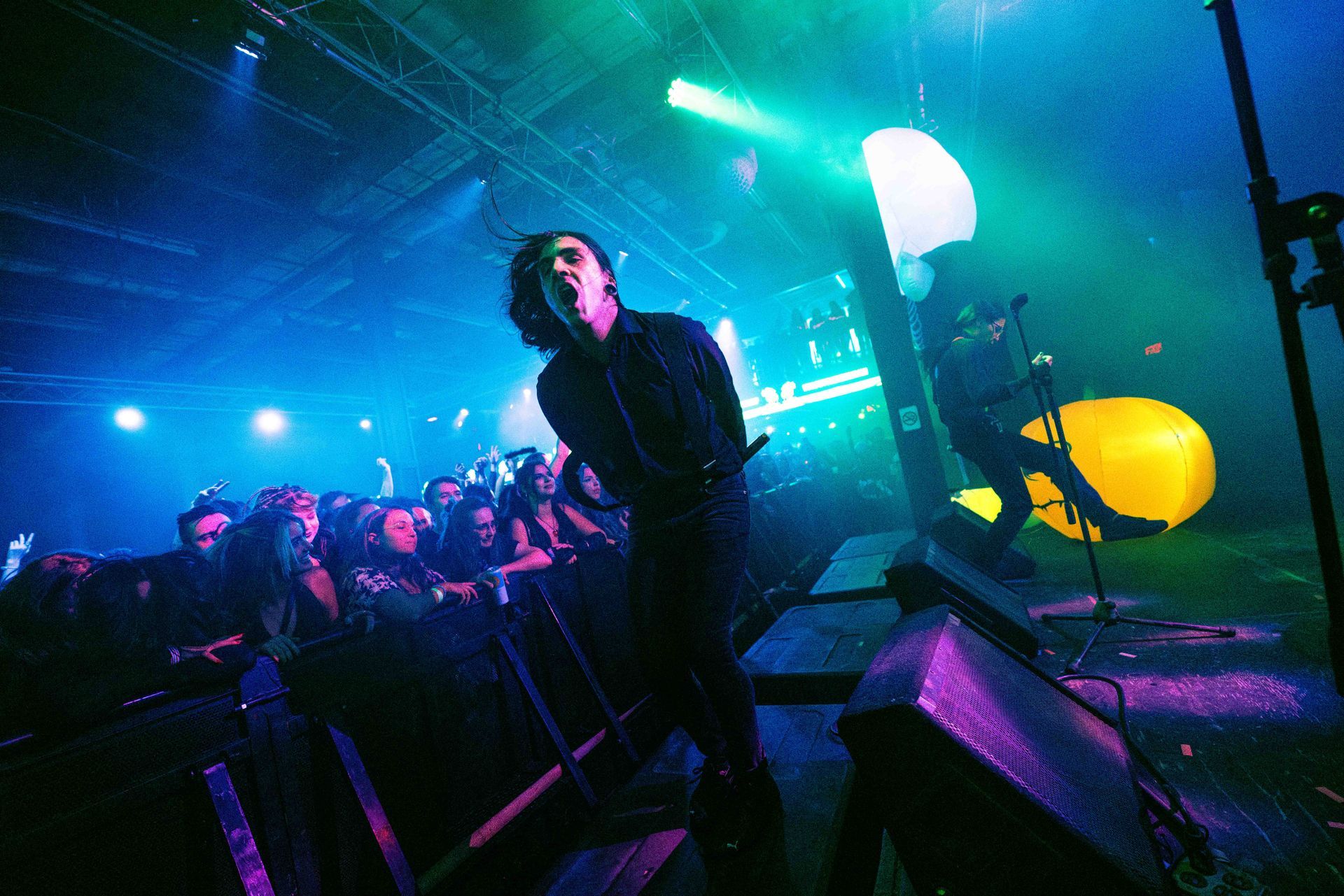 A man is singing into a microphone on a stage in front of a crowd.