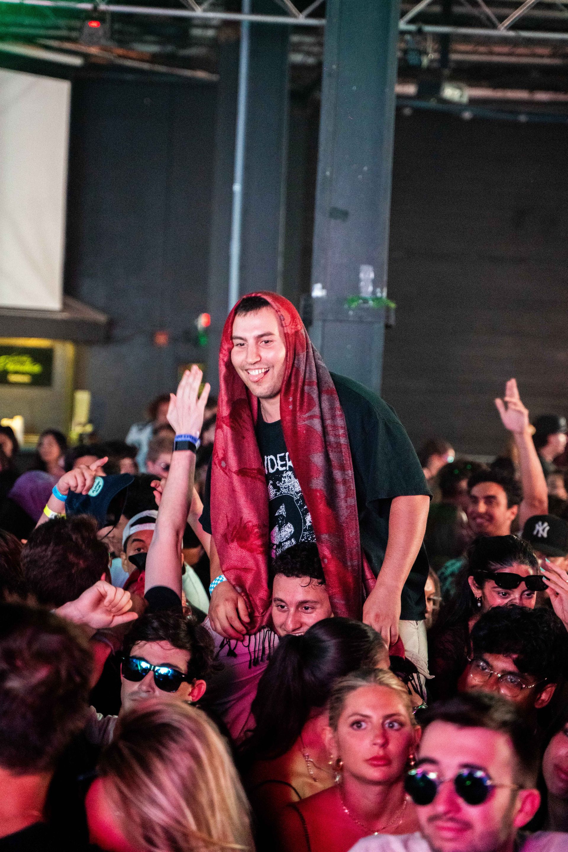 A man is carrying another man on his shoulders in a crowd of people.