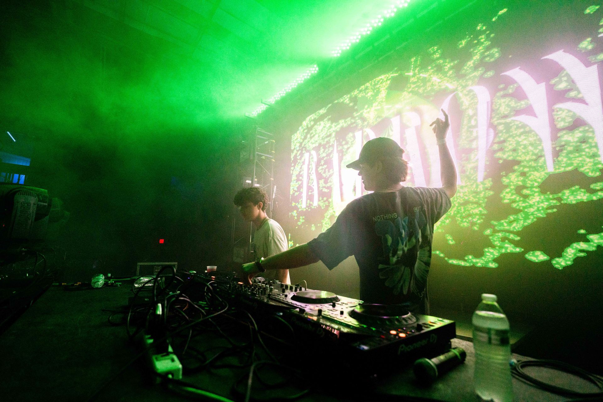 A man is playing a dj set in a dark room with green lights.