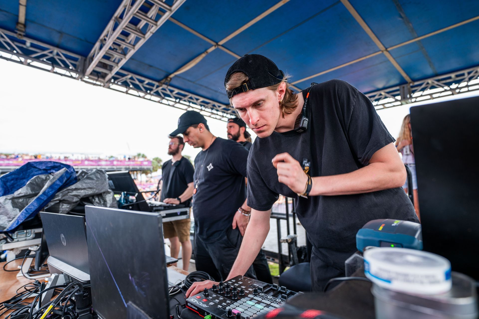 A group of men are standing around a dj booth.