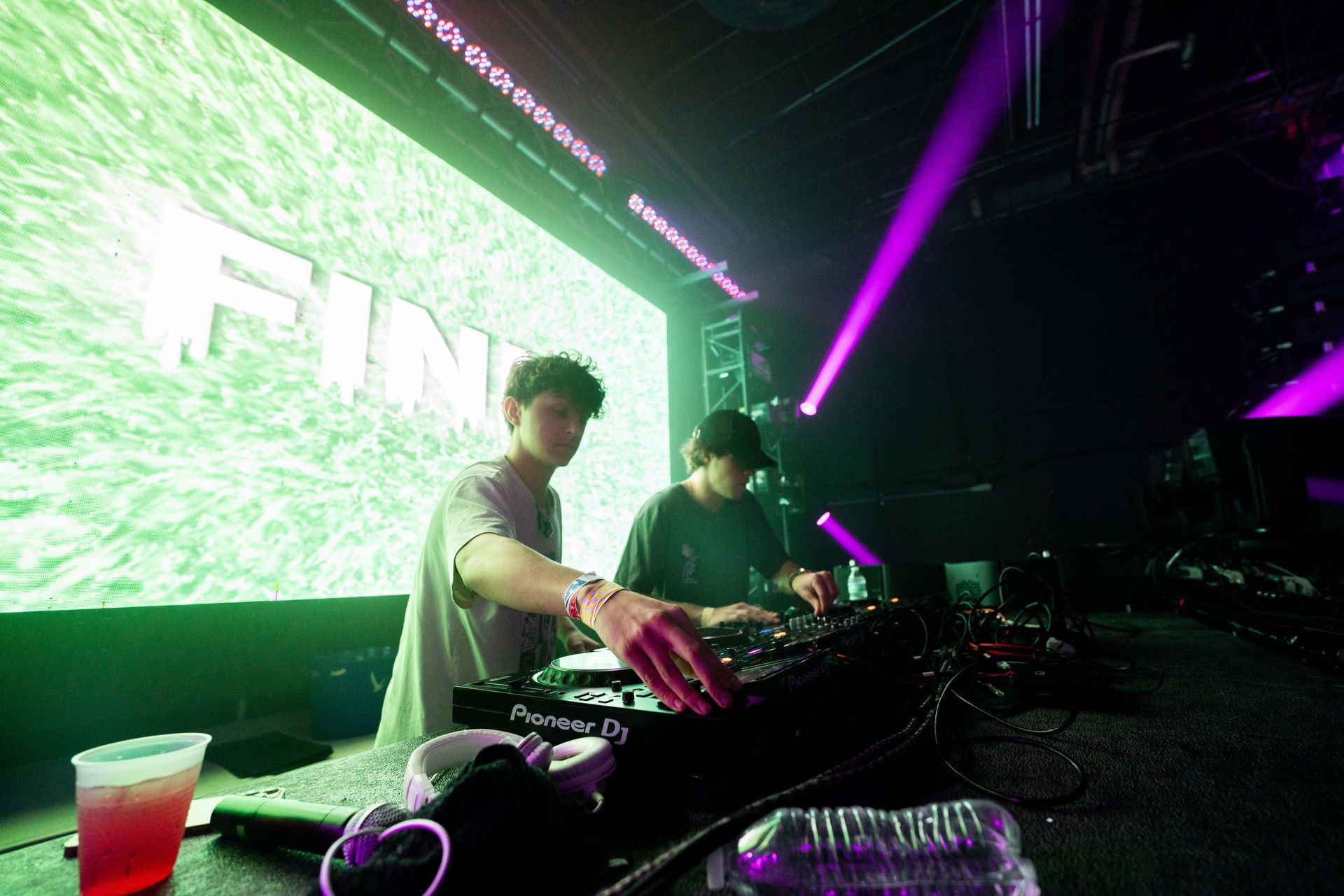 Two men are playing music on a stage in a club.