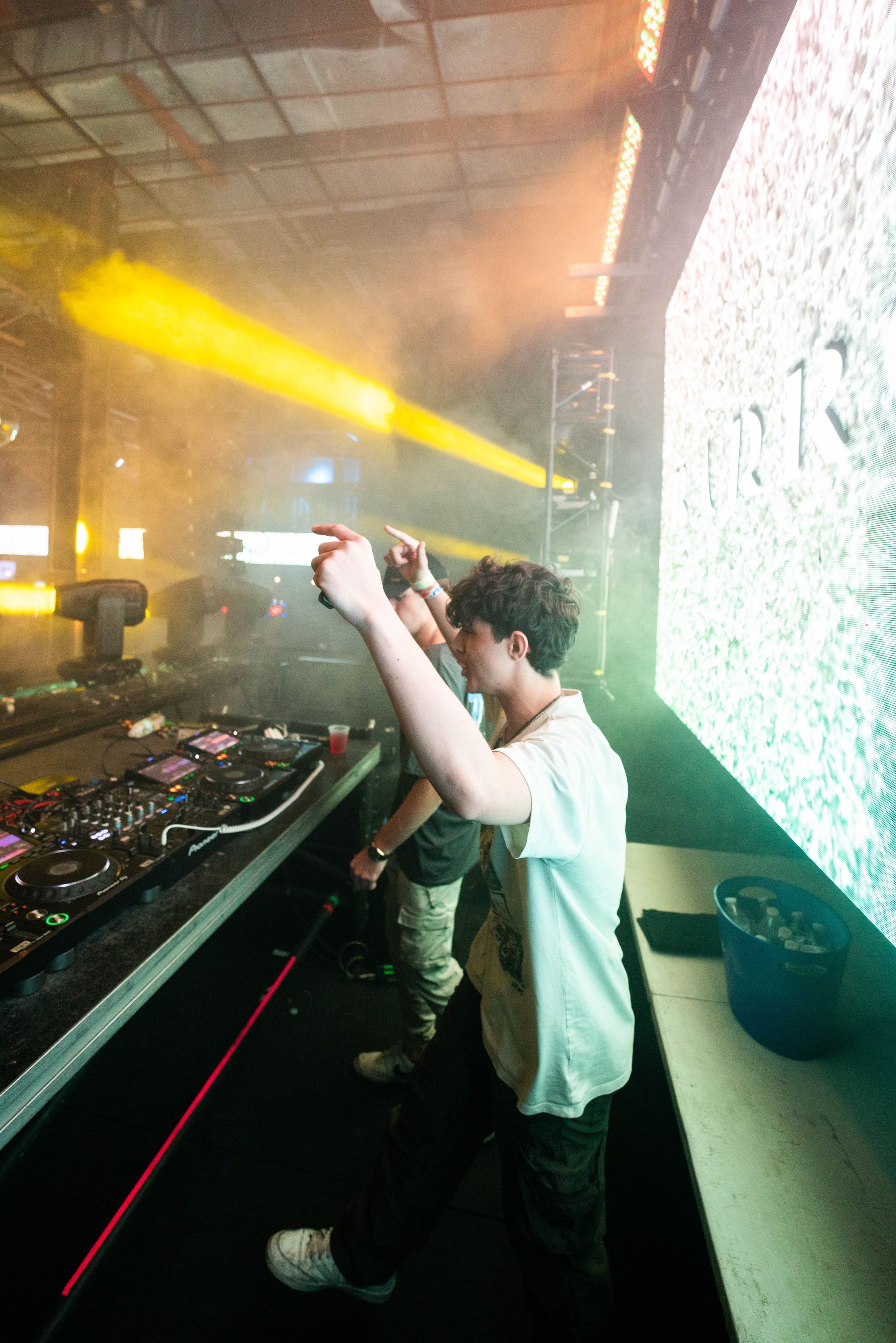 A man is taking a picture of a dj in a club.