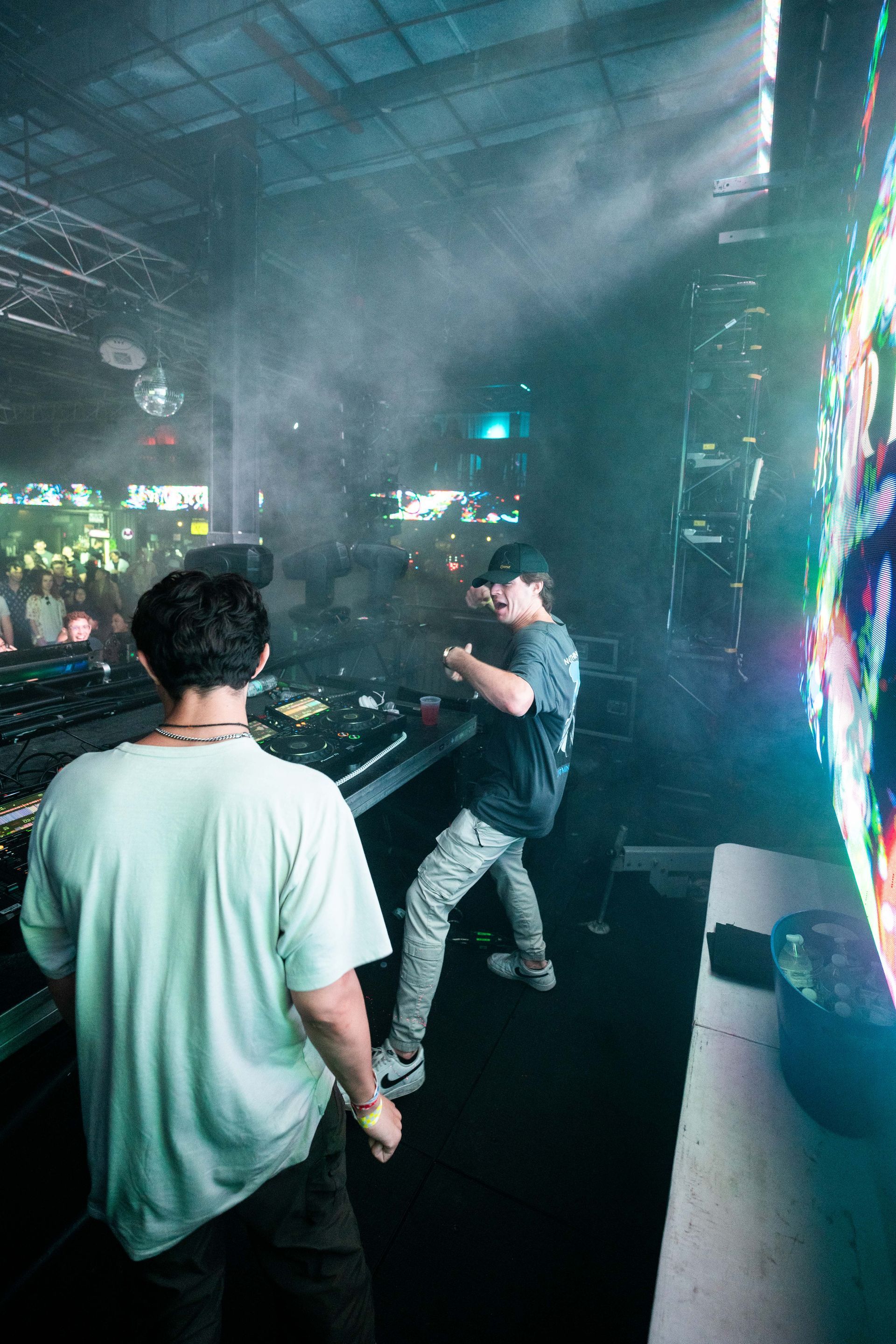 Two men are standing in front of a stage at a concert.