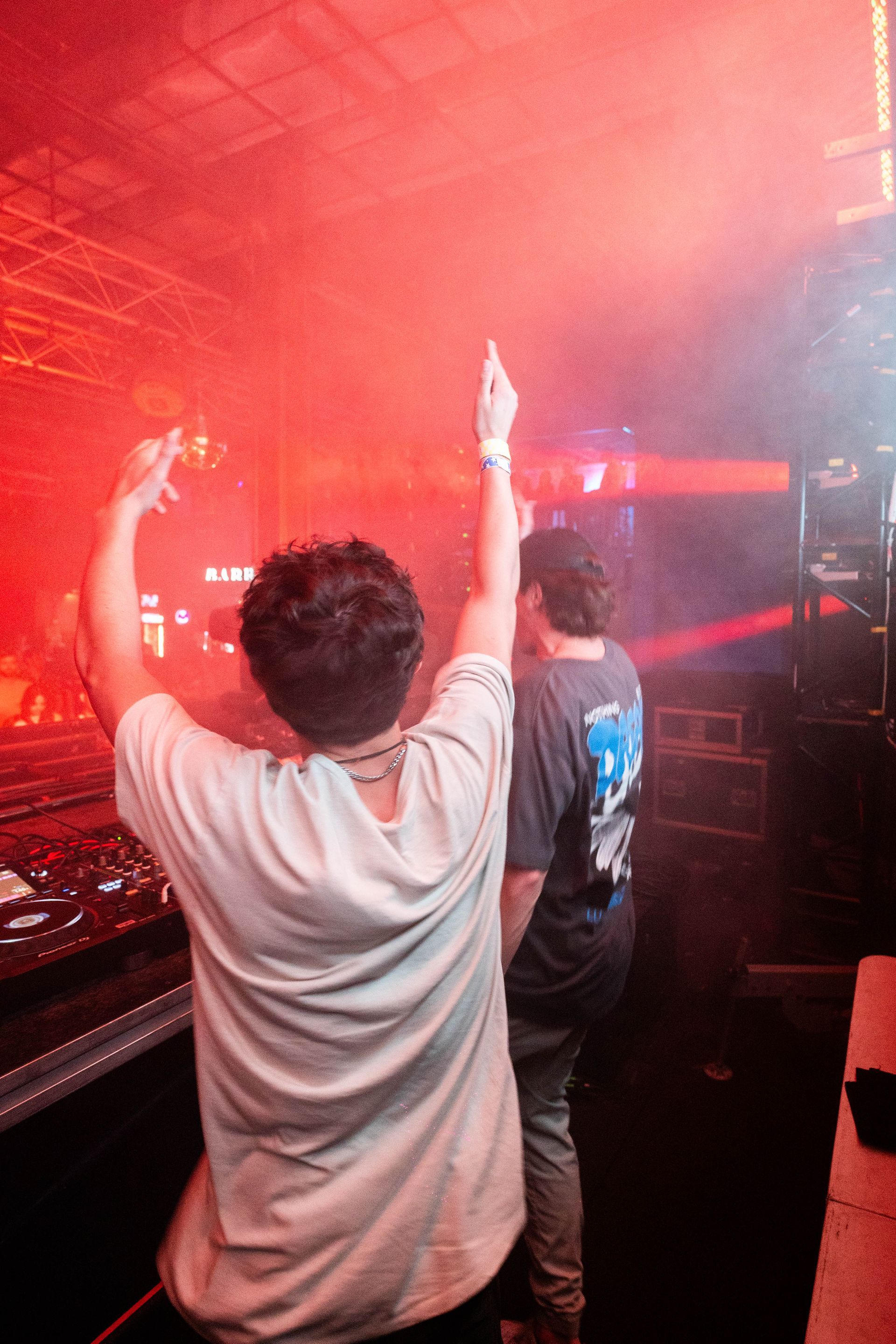 A man is standing in a dark room with his arms in the air.