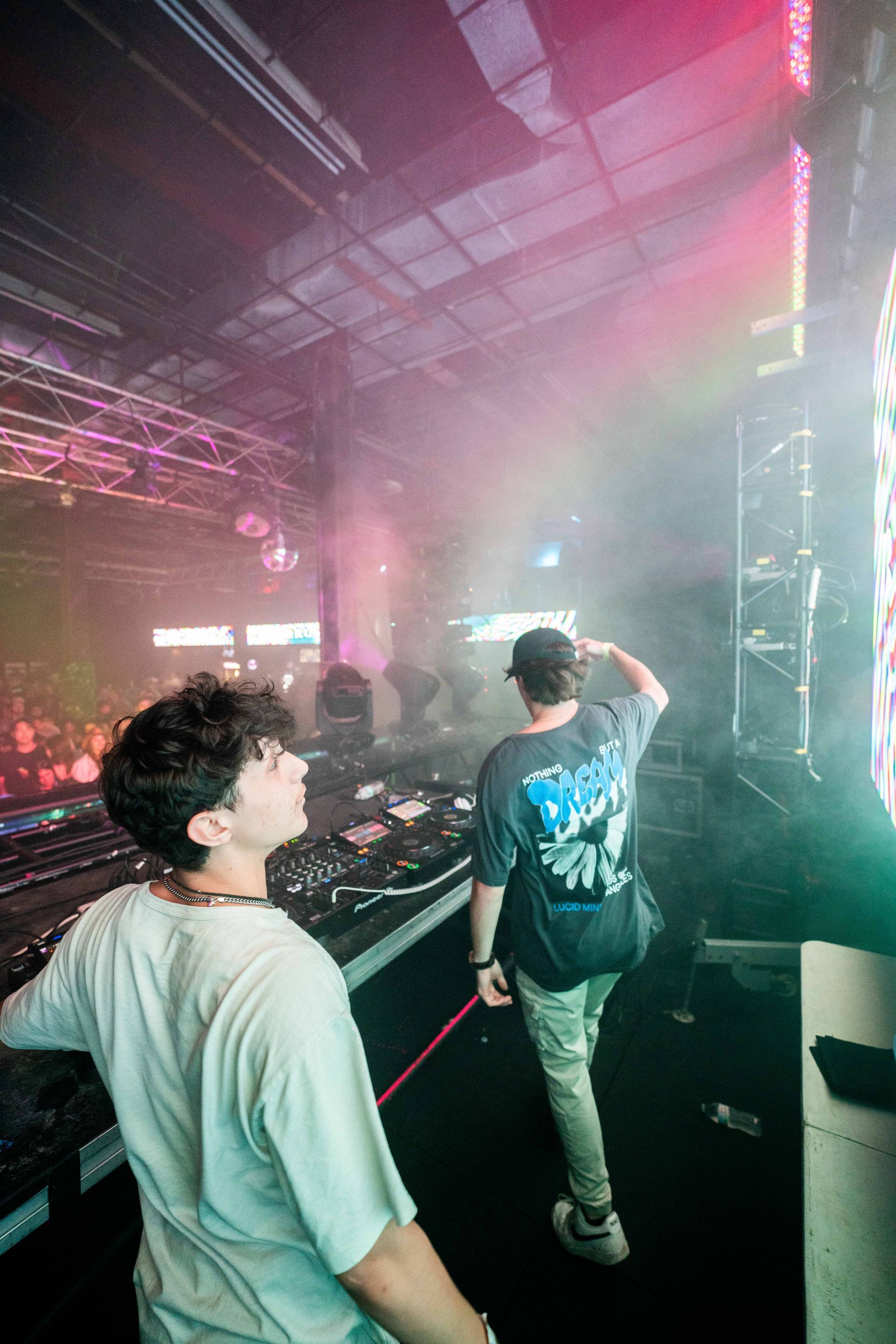 A man is standing in front of a dj booth at a concert.