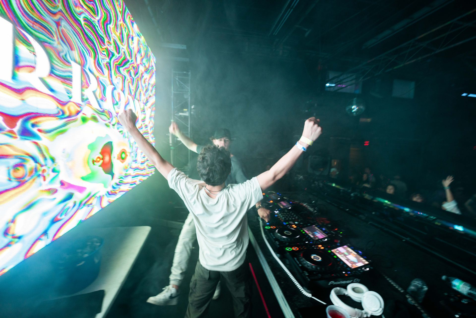 A man is standing on a stage with his arms in the air.