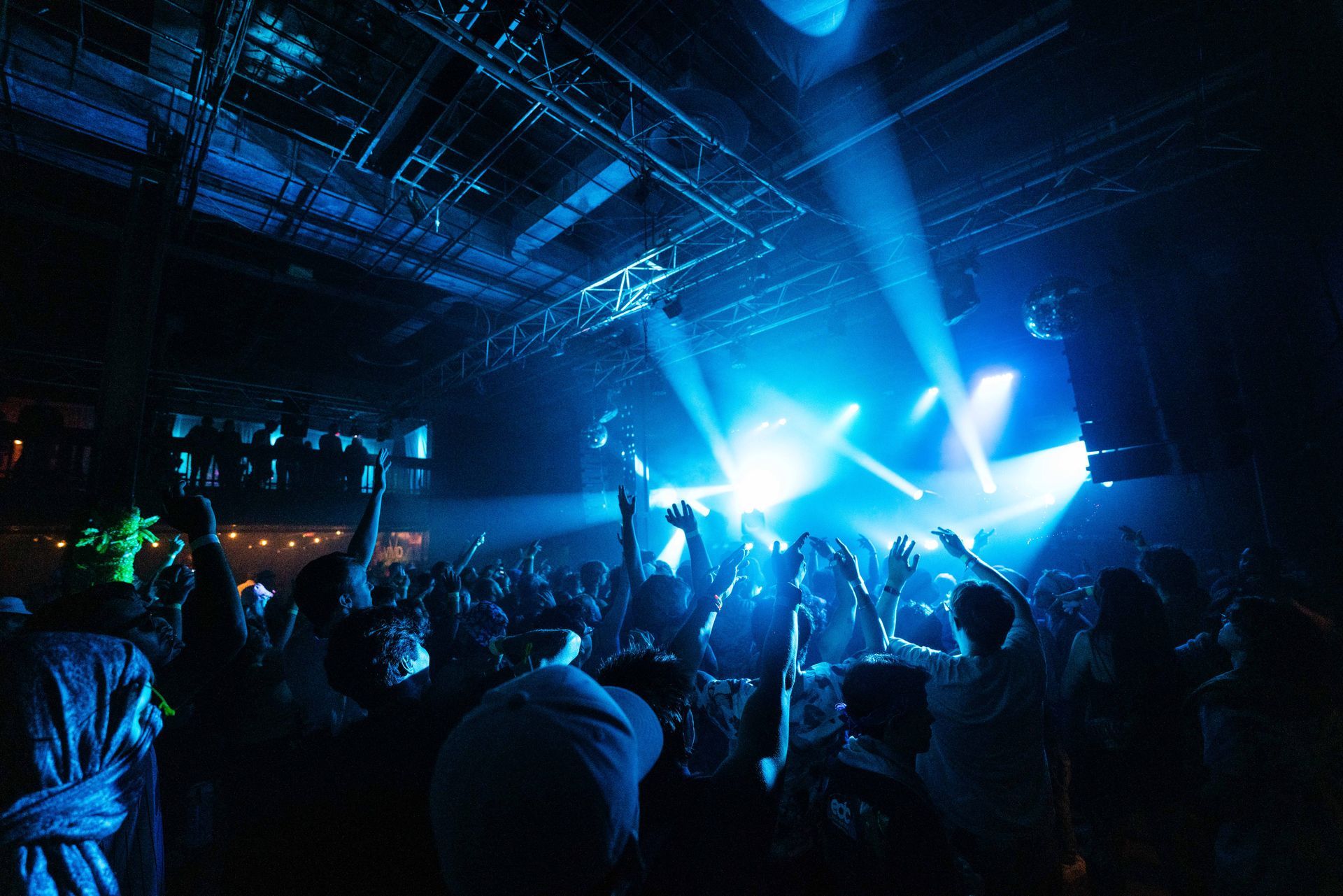 A crowd of people at a concert with their hands in the air