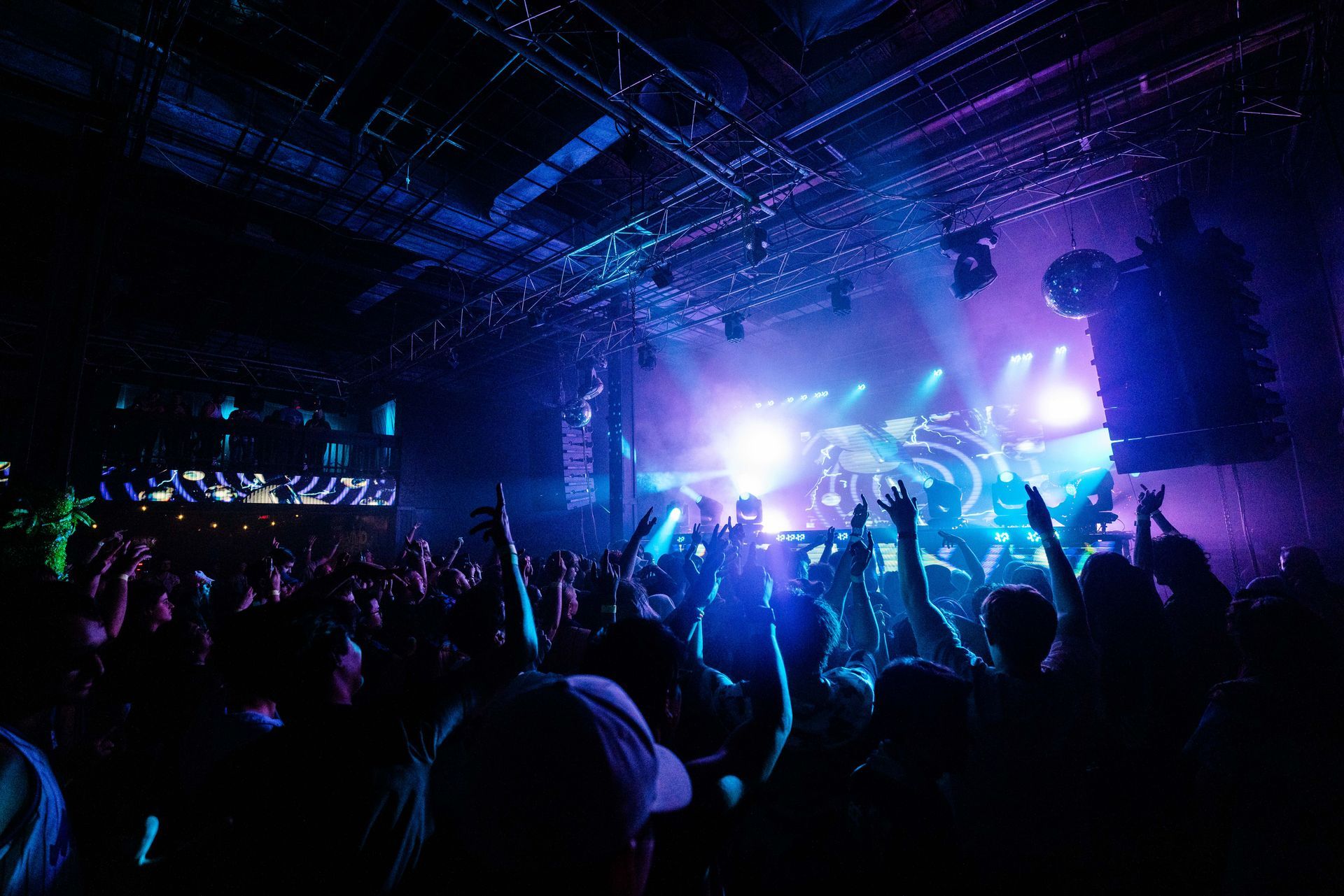 A crowd of people at a concert with their hands in the air