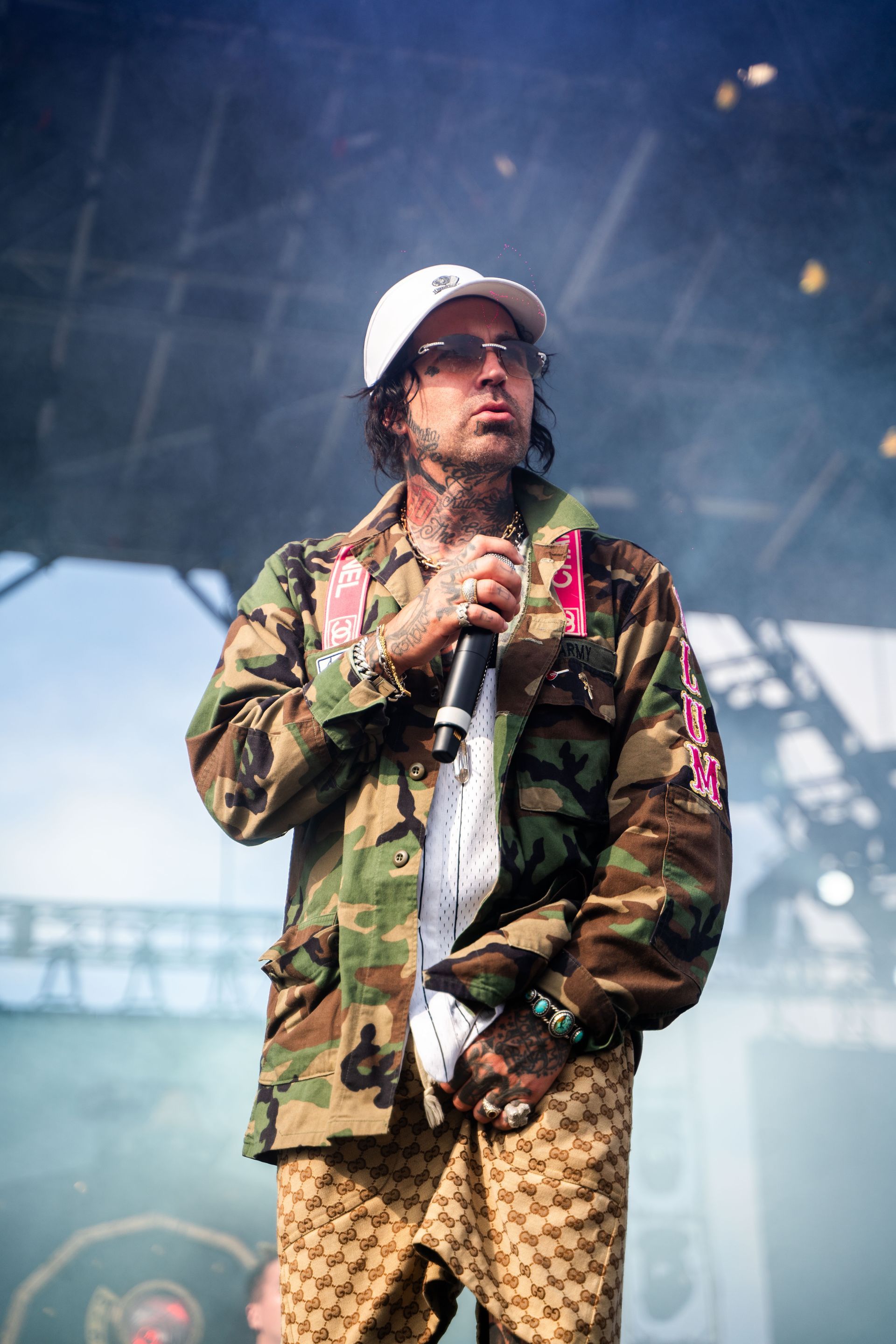 A man in a camouflage jacket is standing on a stage holding a microphone.