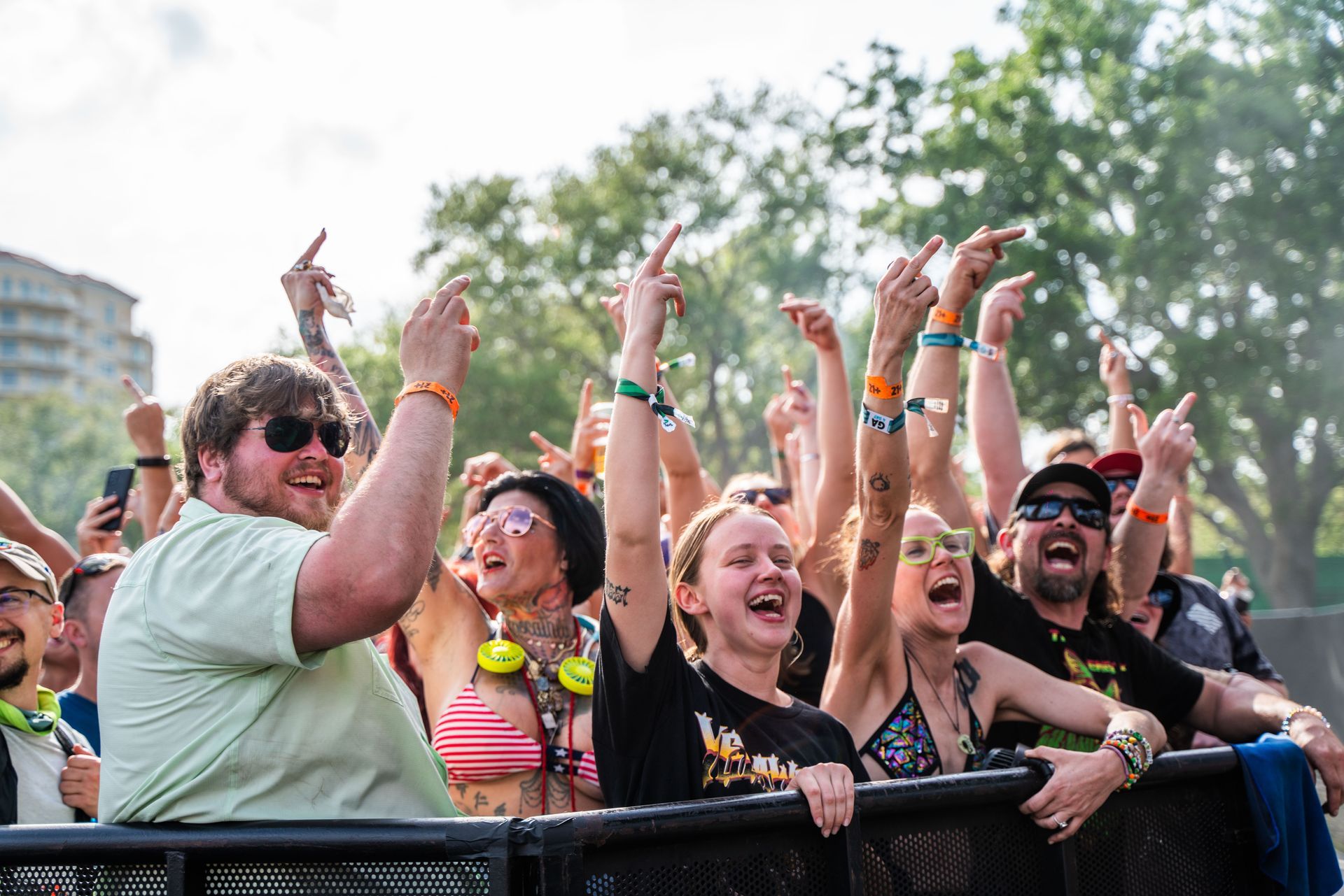 A crowd of people are standing behind a fence at a concert.