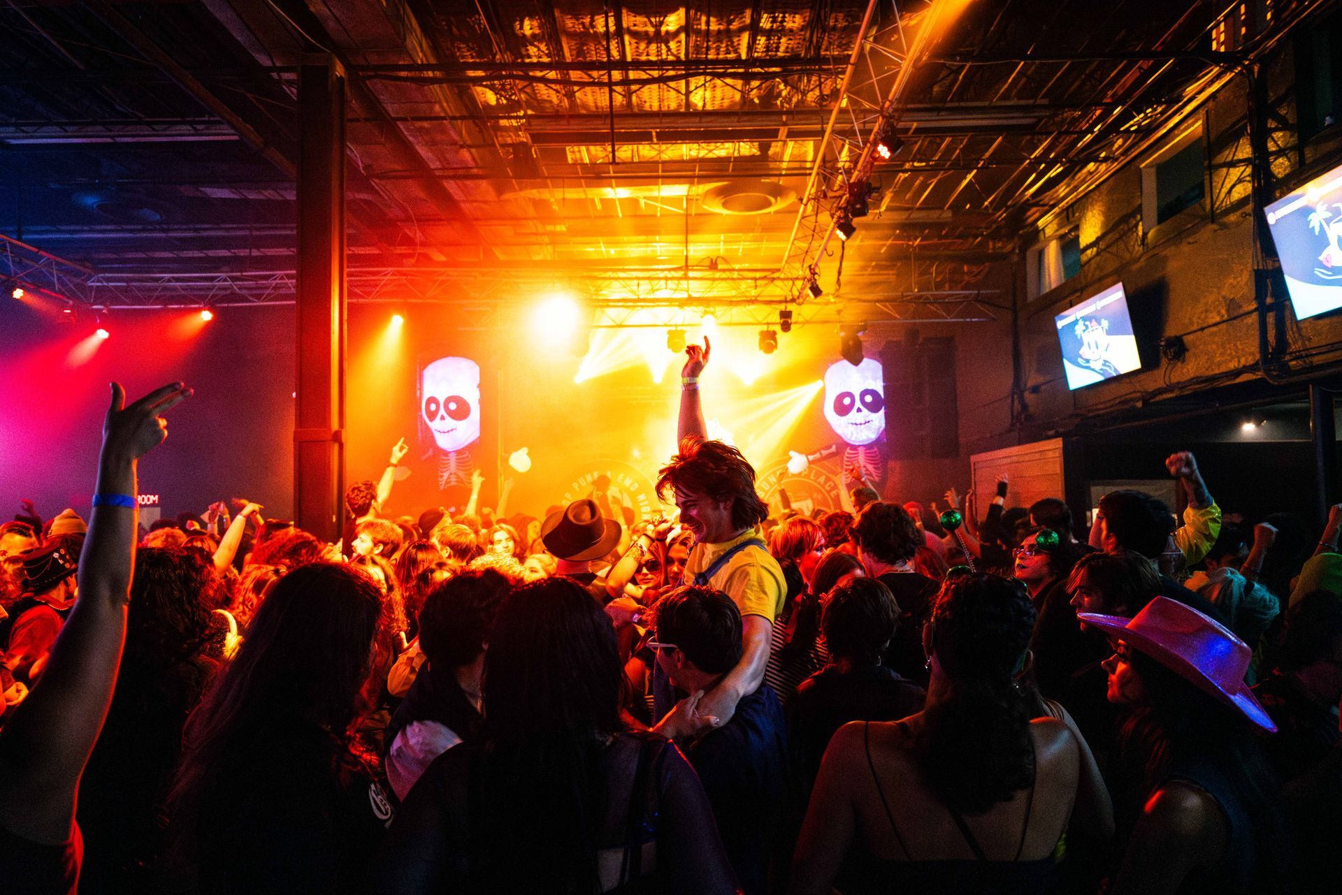 A crowd of people are dancing in a club at a concert.