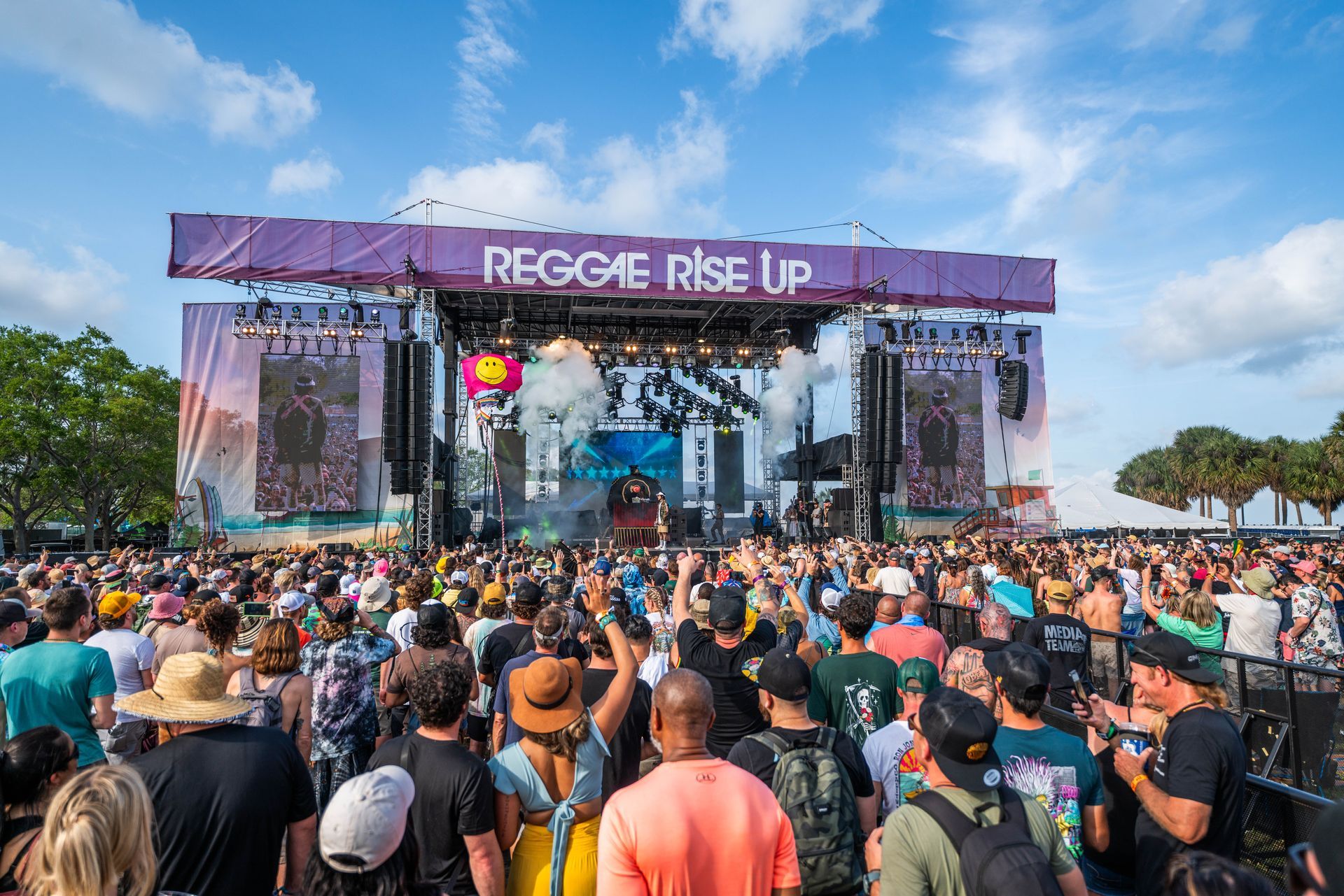 A crowd of people are standing in front of a stage at a music festival.