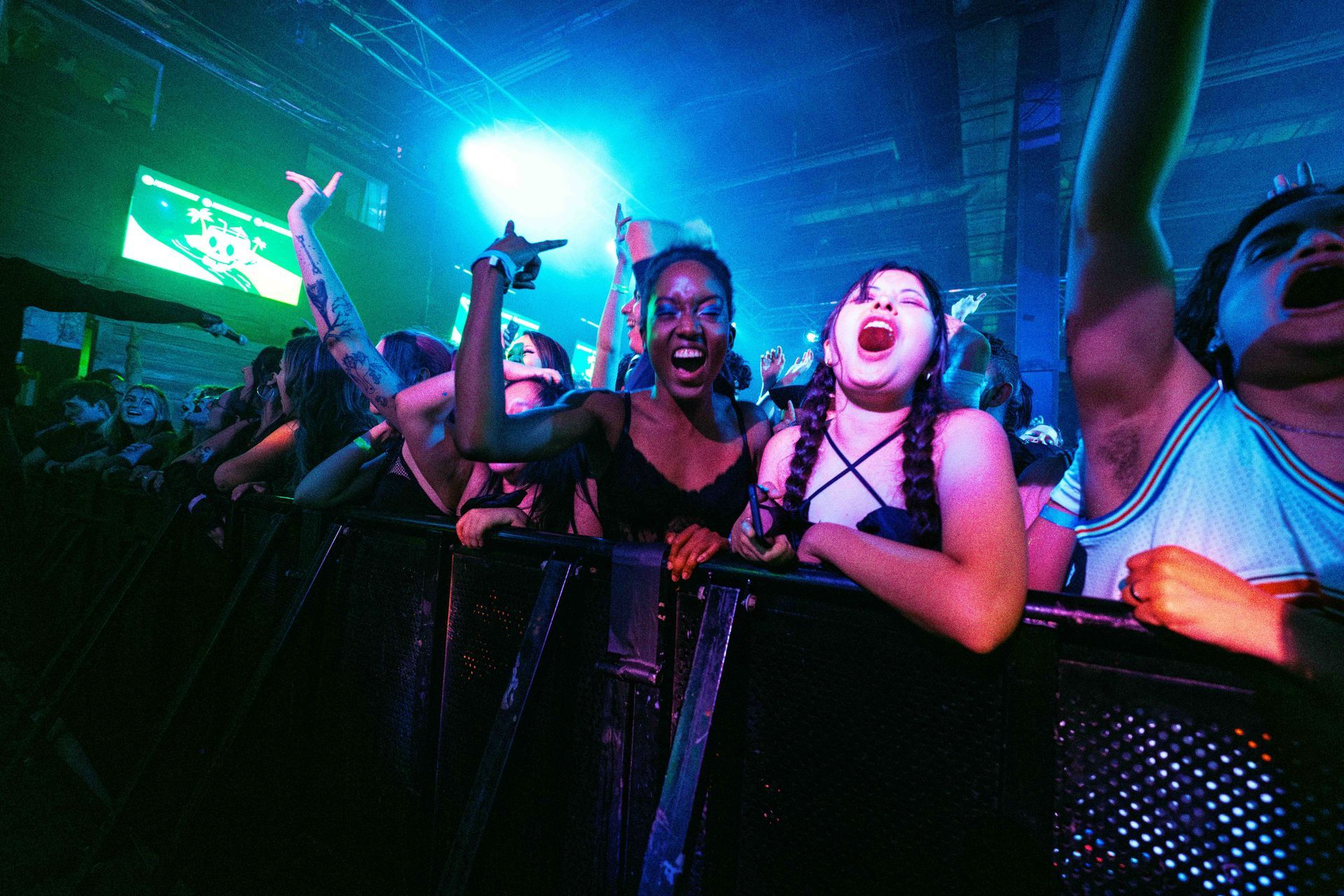 A group of people are standing in a dark room with their arms in the air.