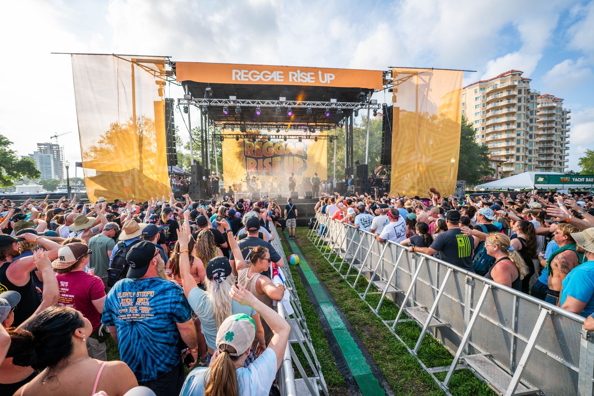 A crowd of people are standing in front of a stage at a music festival.