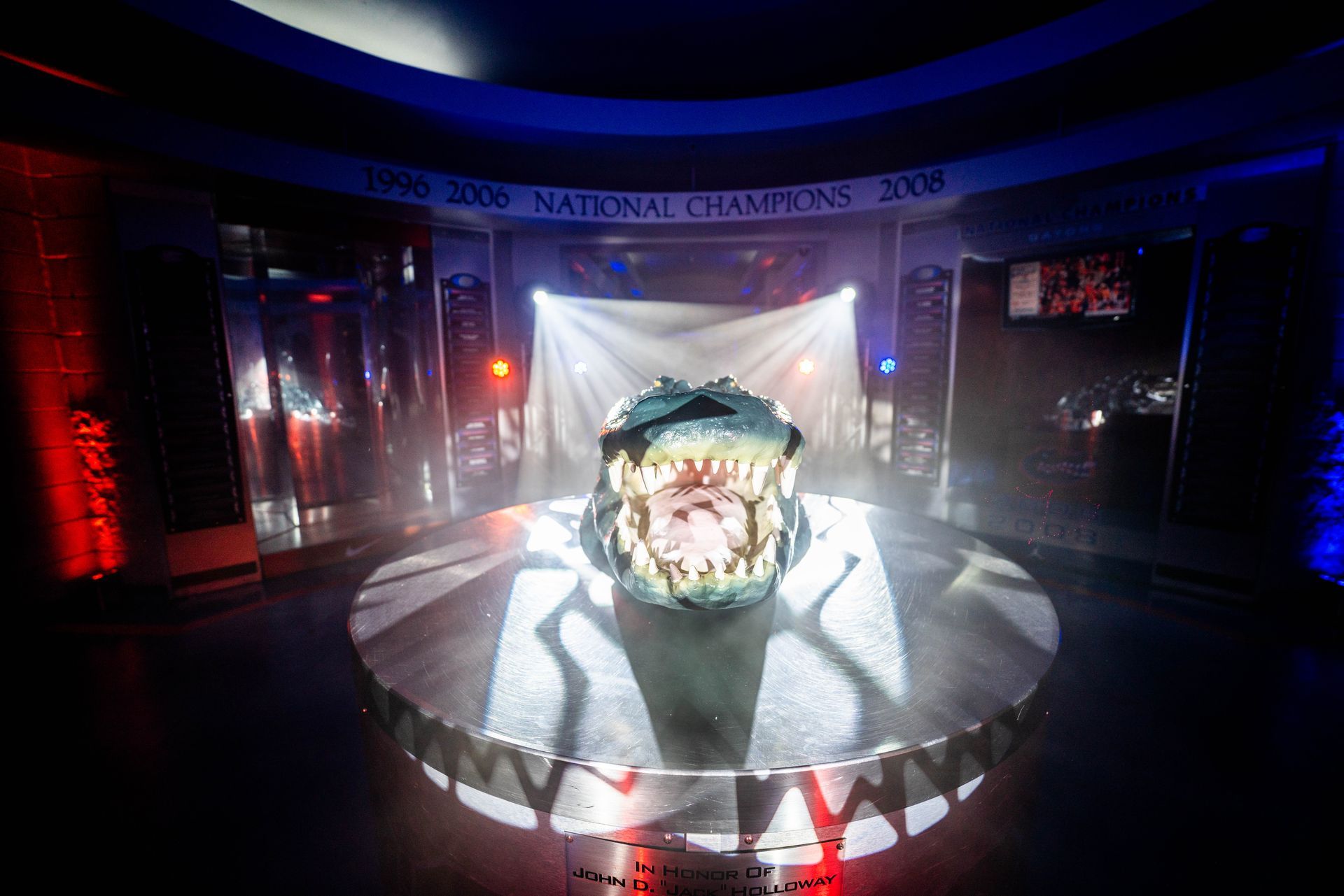 A statue of a dinosaur is sitting on a round table in a dark room.