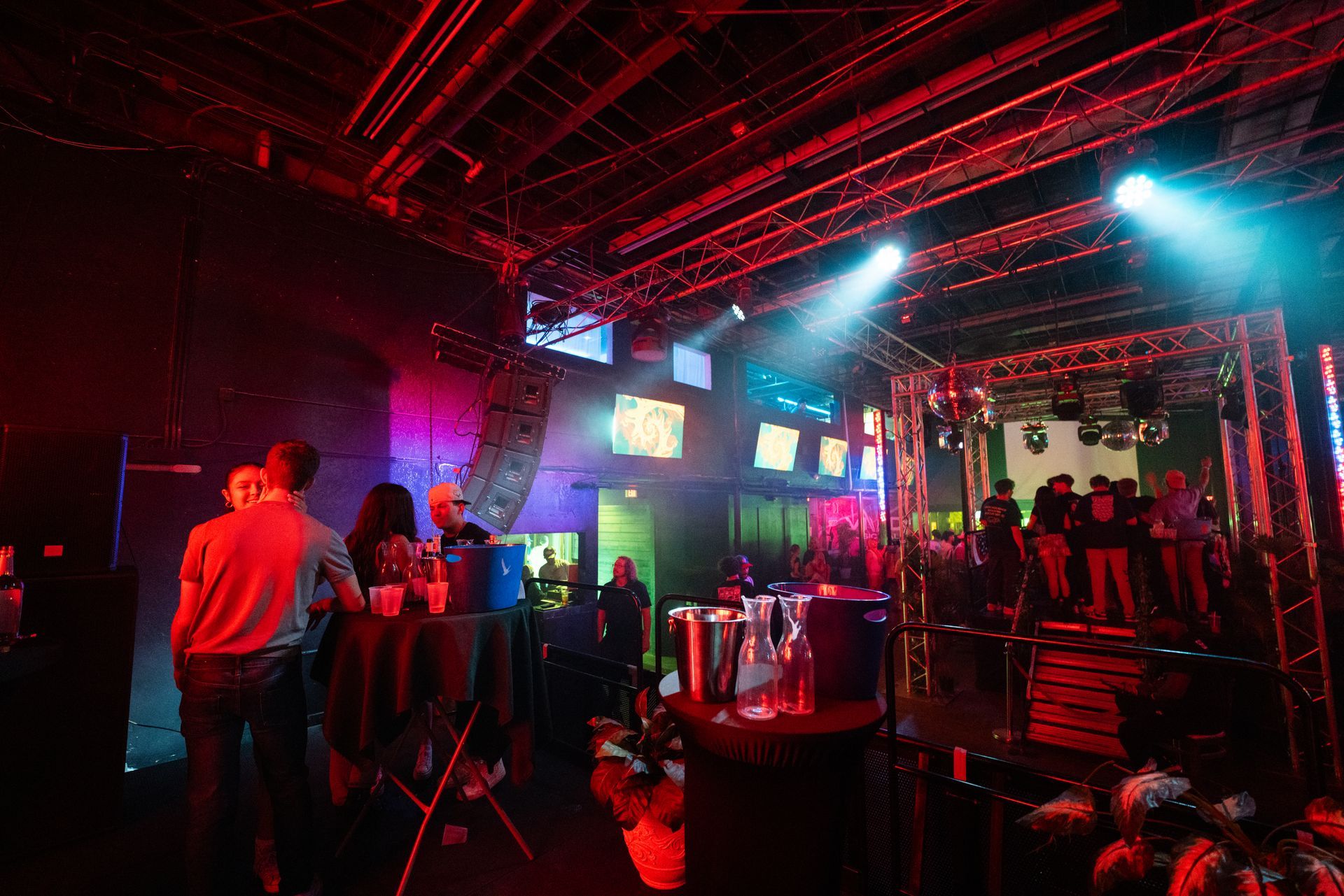 A group of people are standing in a dark room with red lights.
