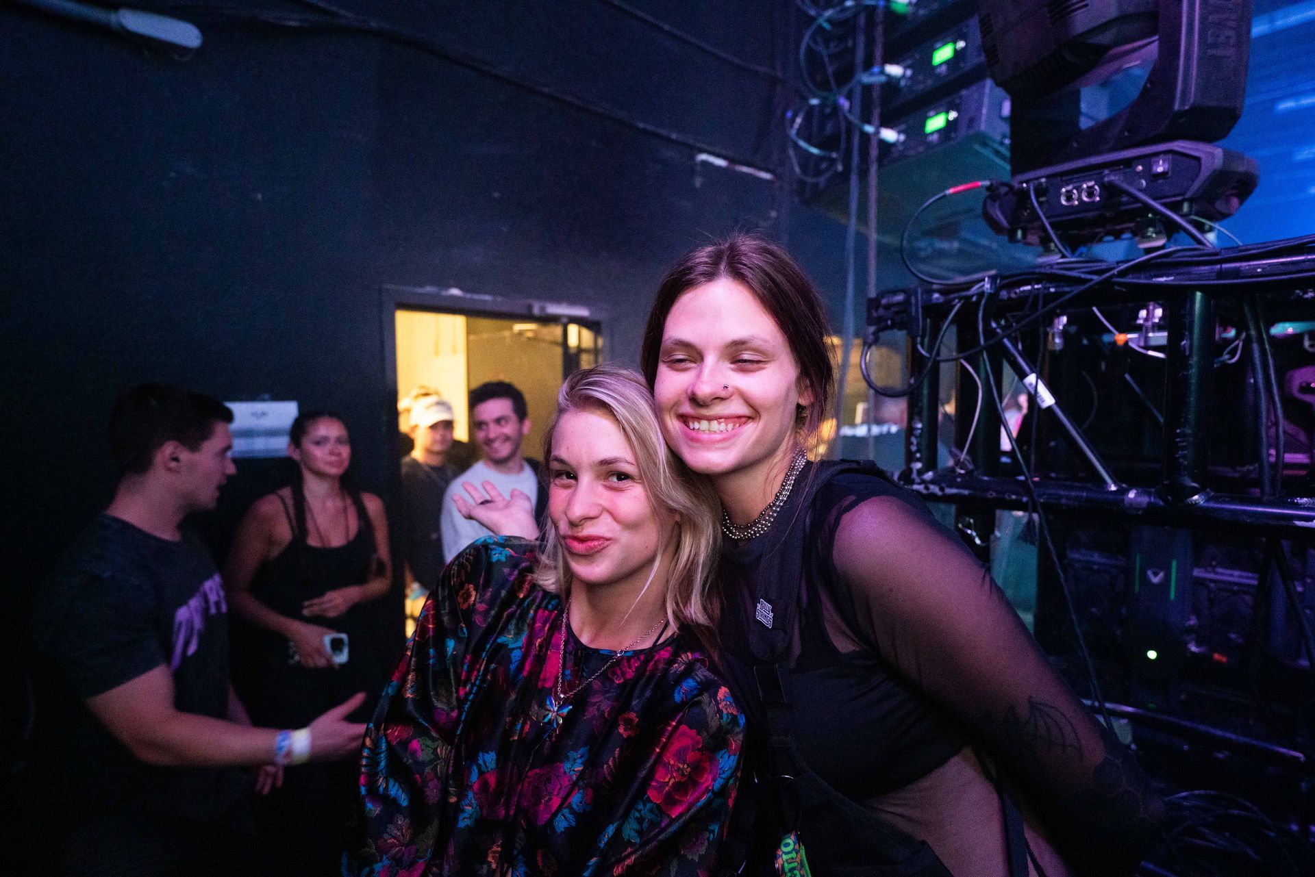 Two women are posing for a picture in a dark room.