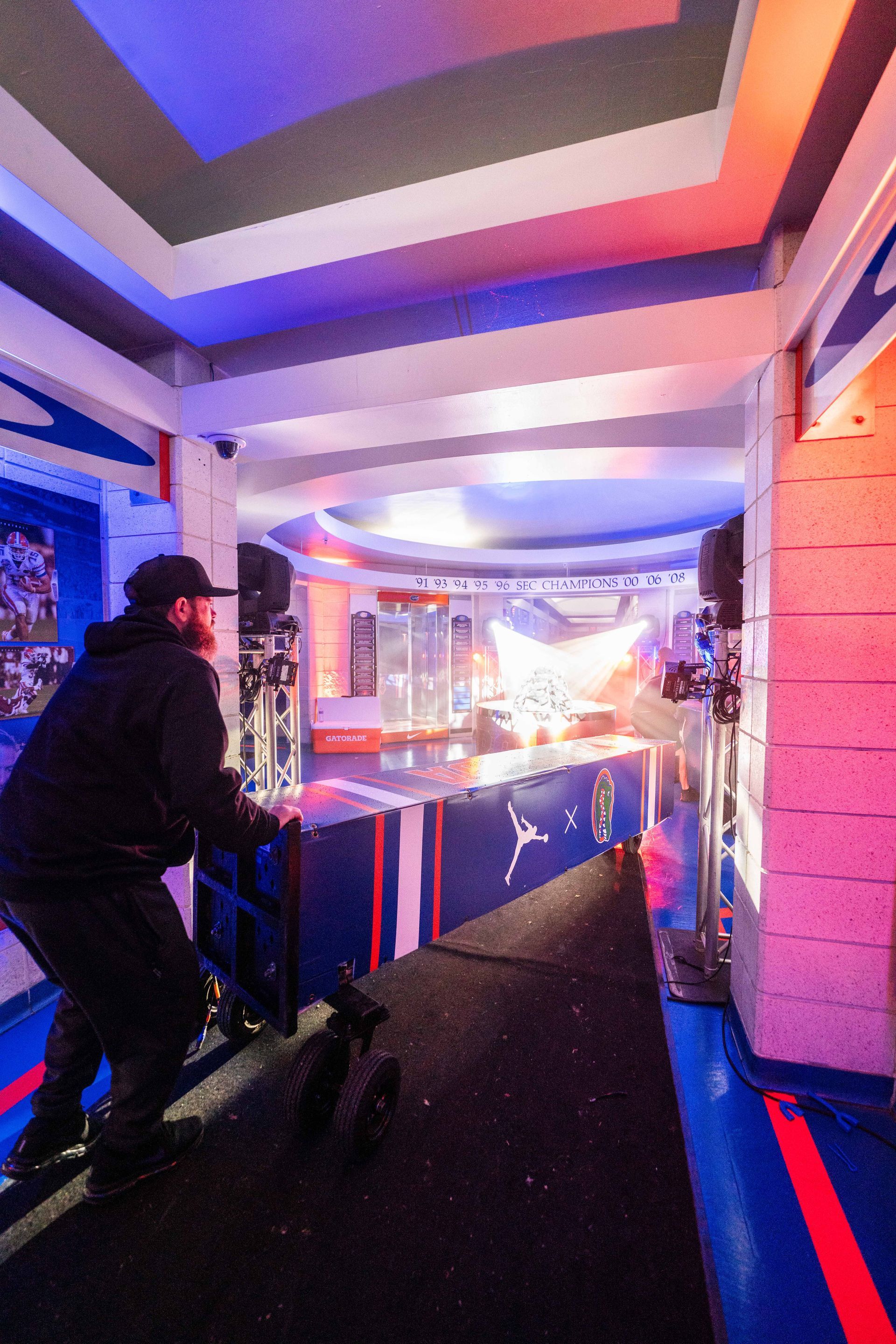 A man is pushing a scooter down a ramp in a room.