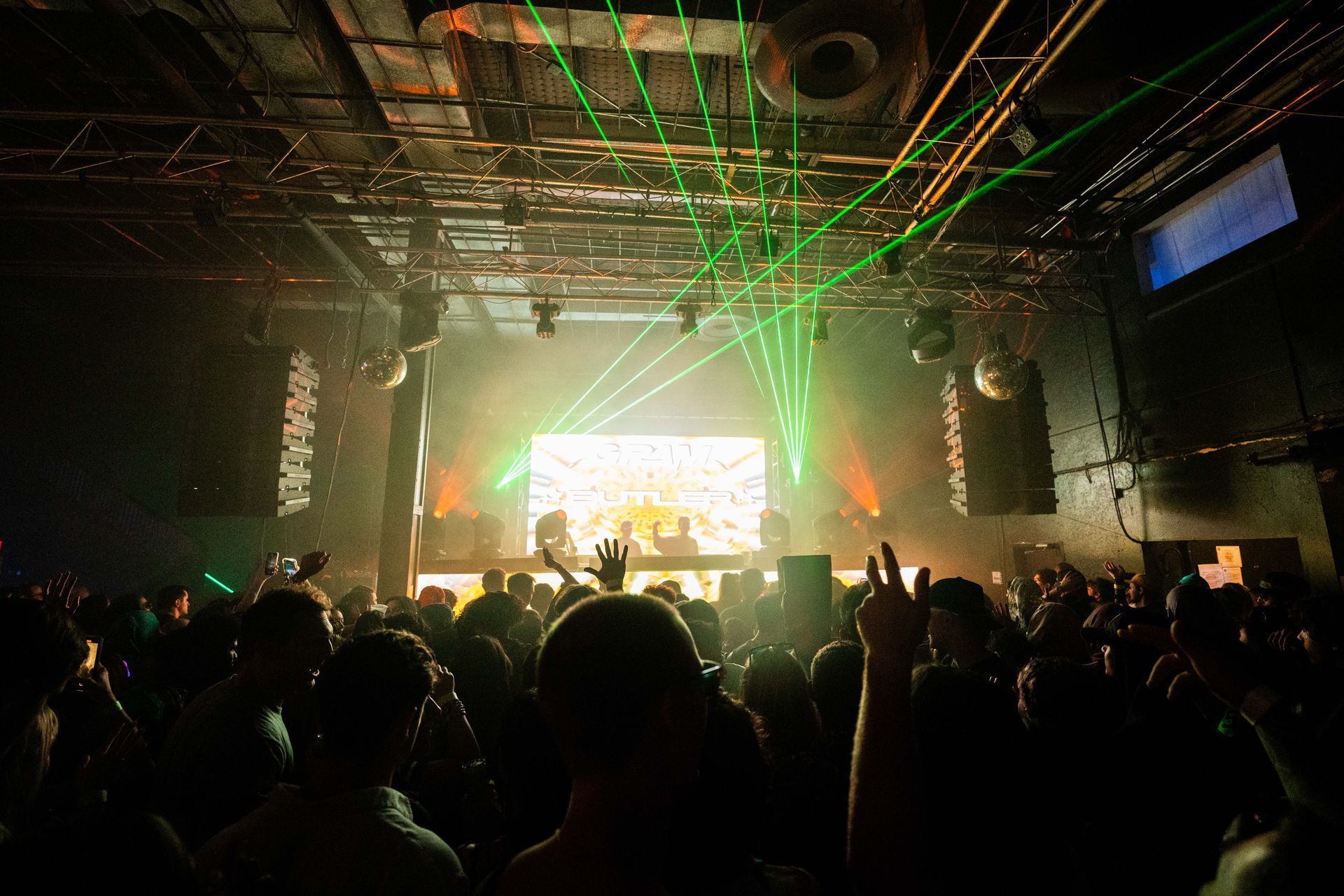 A crowd of people are standing in front of a stage at a concert.