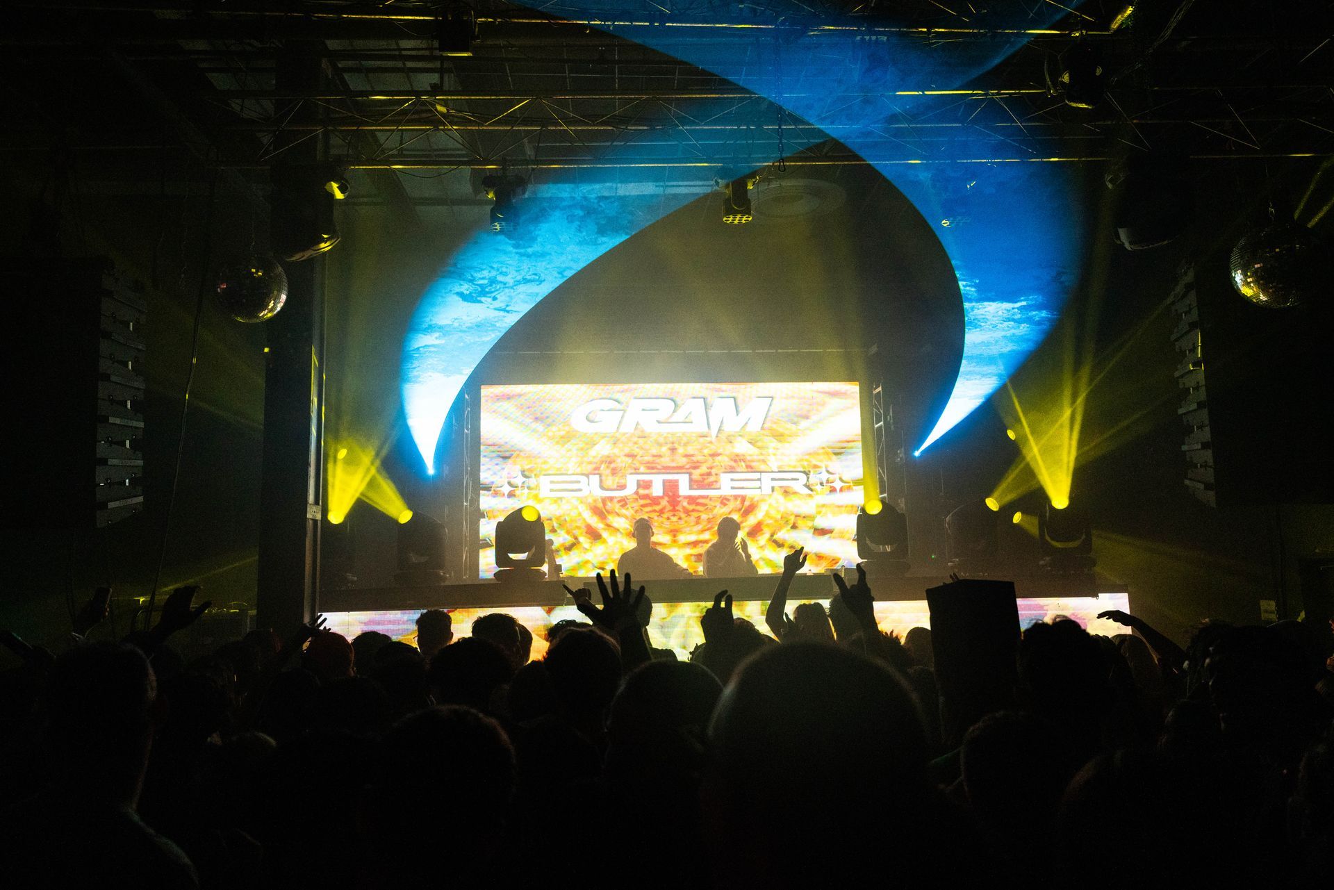 A crowd of people at a concert watching a dj perform