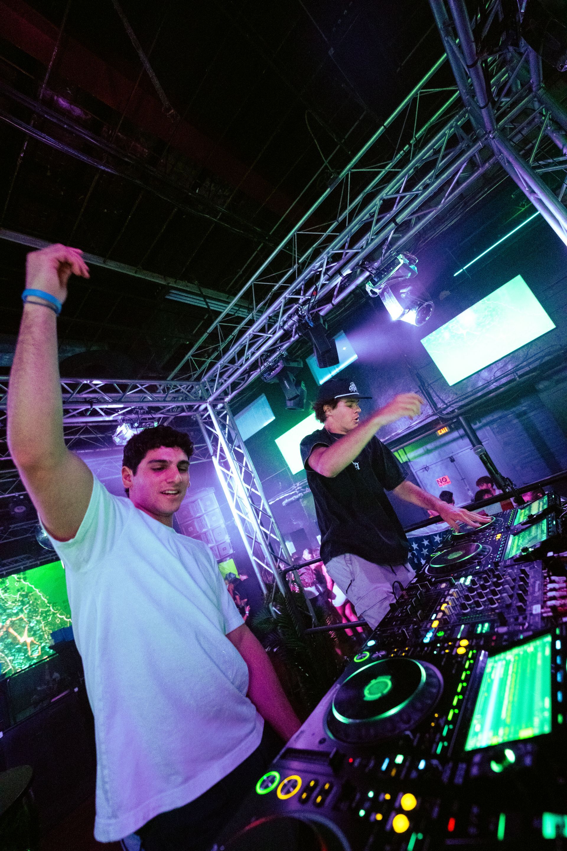 A man is standing in front of a dj mixer in a club.