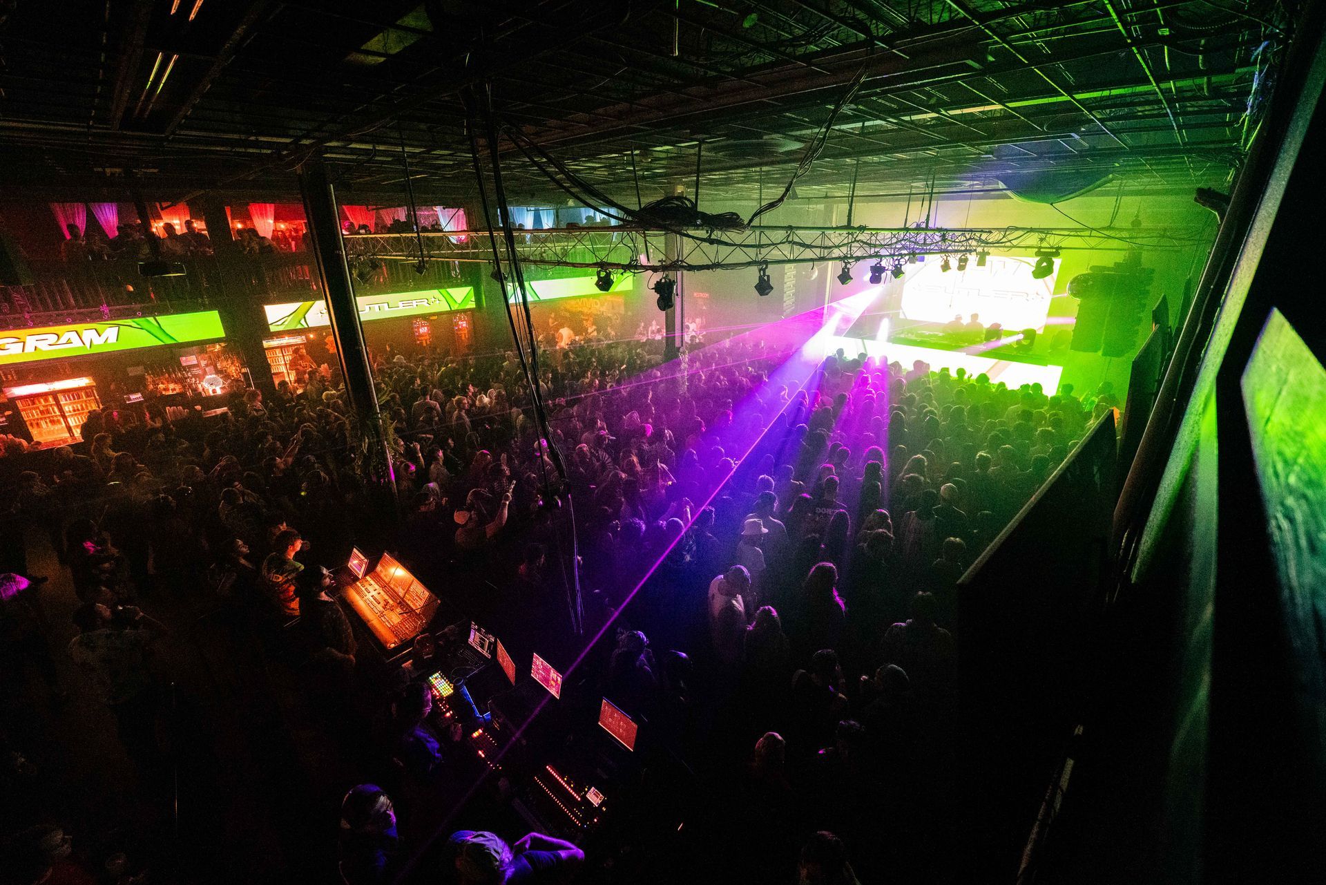 A large crowd of people are gathered in a dark room at a concert.