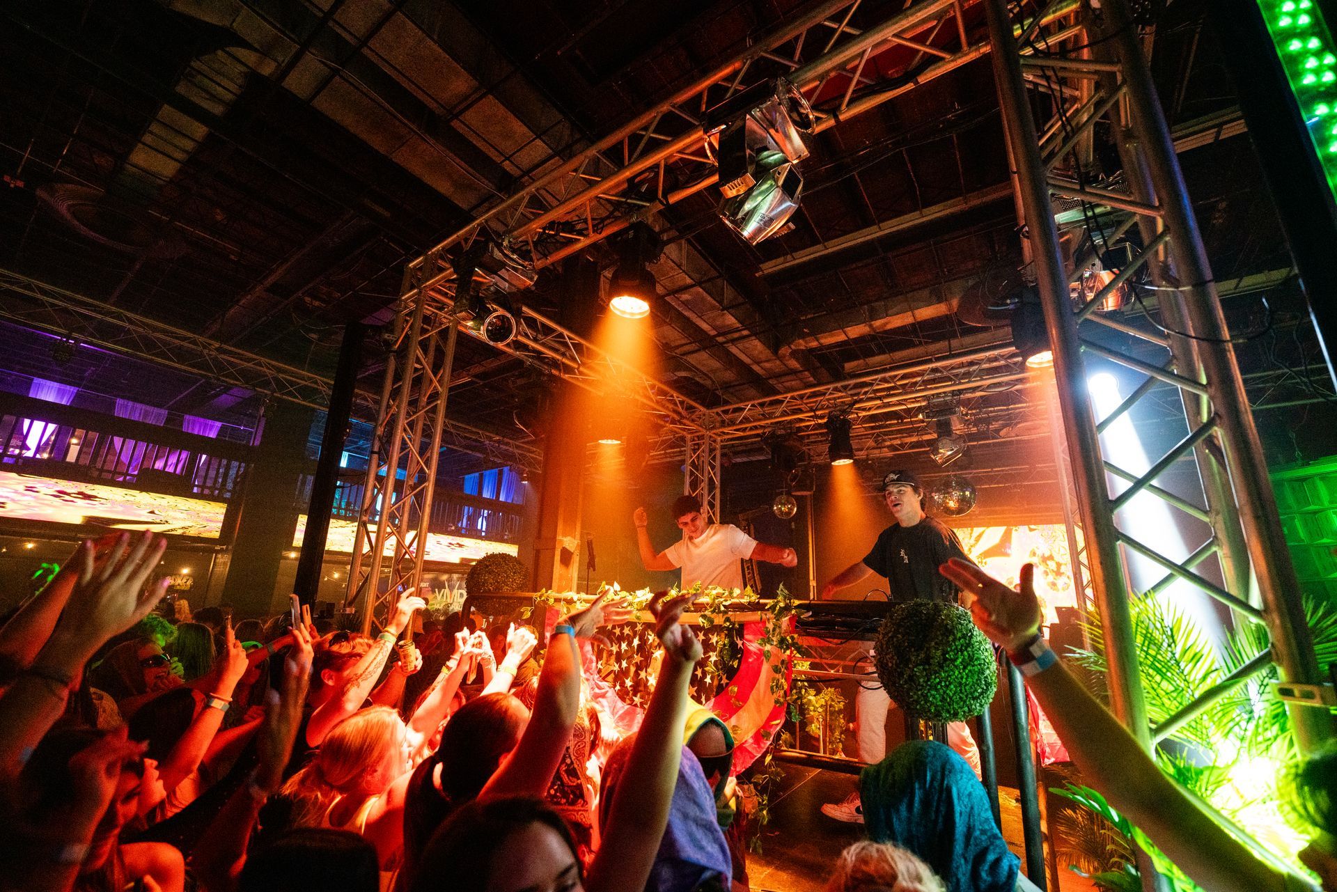 A crowd of people at a concert with their hands in the air