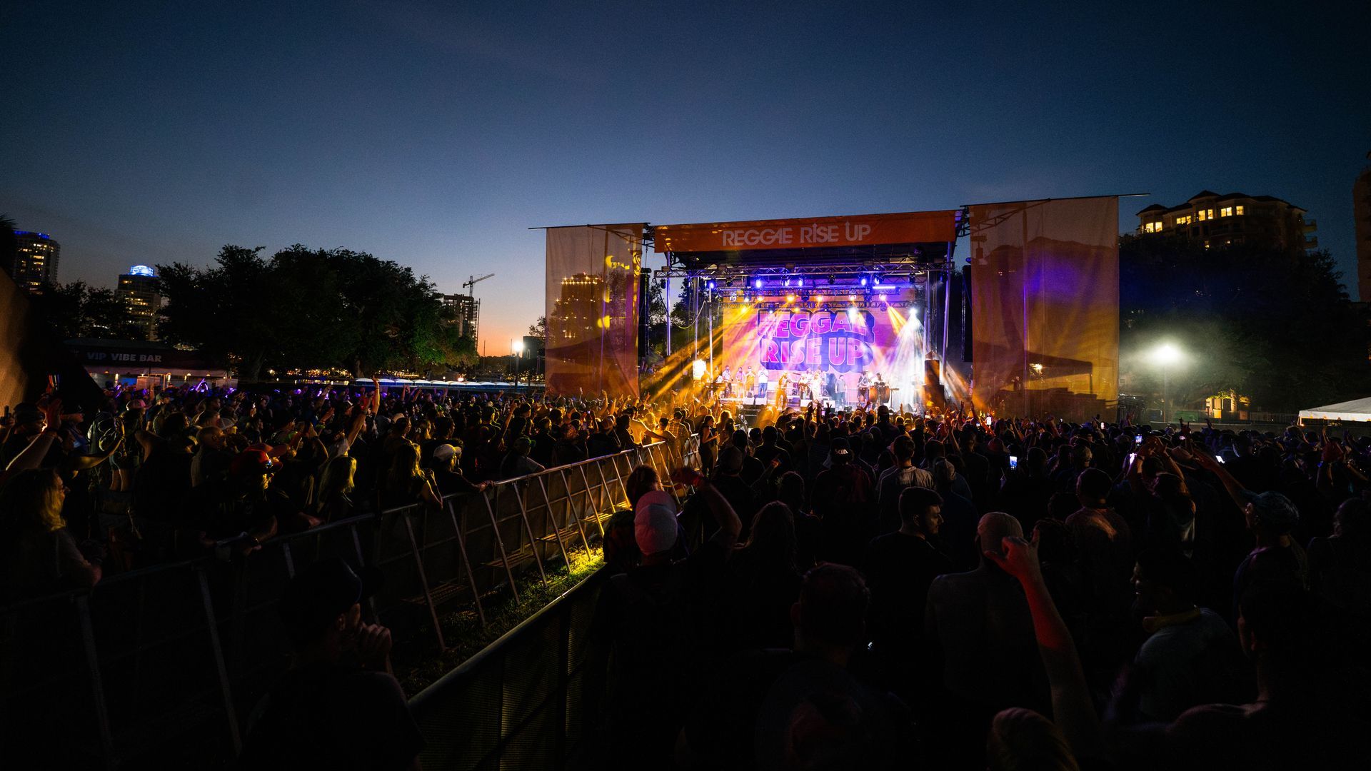 A crowd of people are standing in front of a stage at a concert.