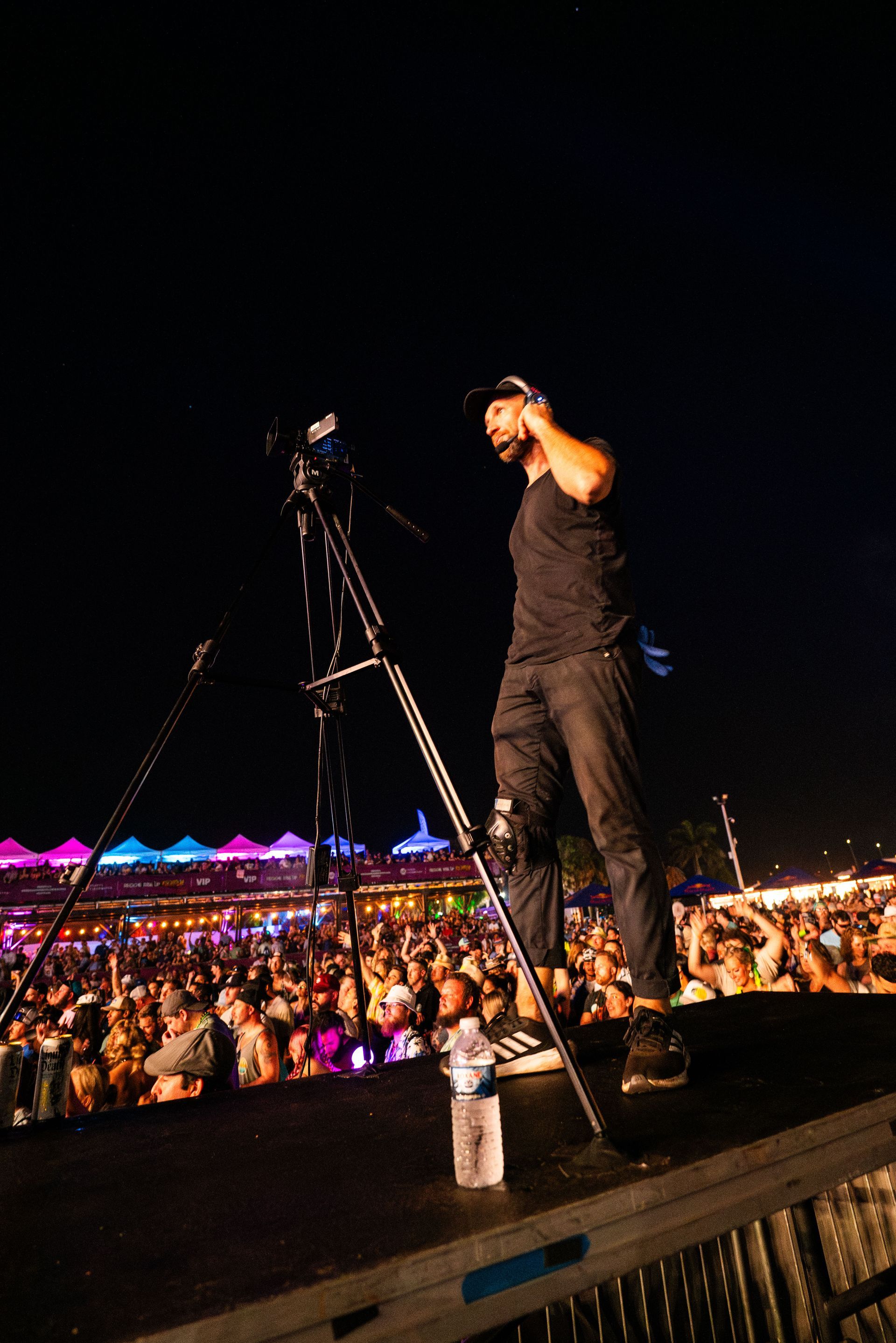 A man is standing on a stage holding a microphone in front of a crowd.