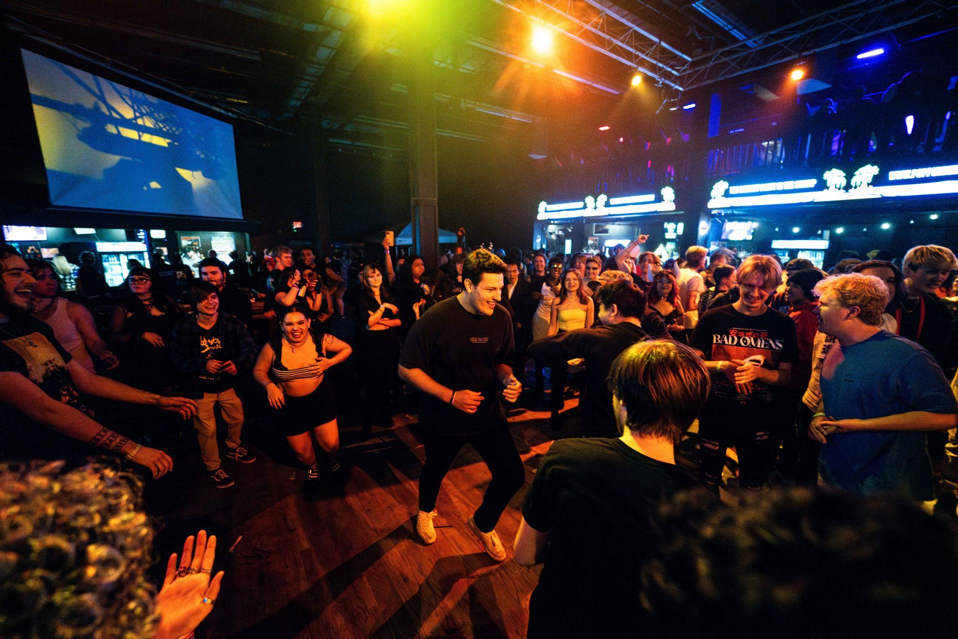 A large crowd of people are dancing in a dark room