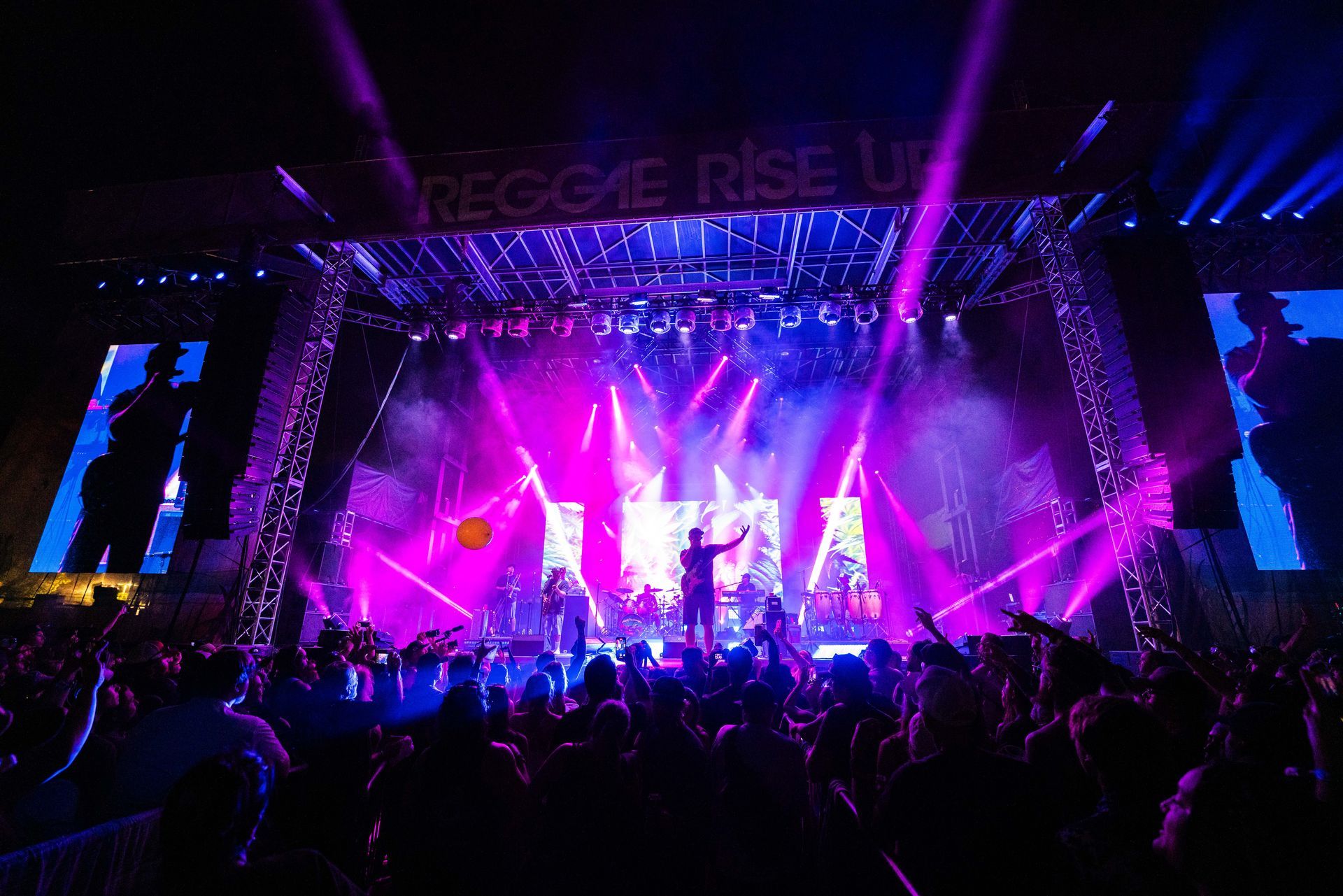 A group of people are standing in front of a stage at a concert.