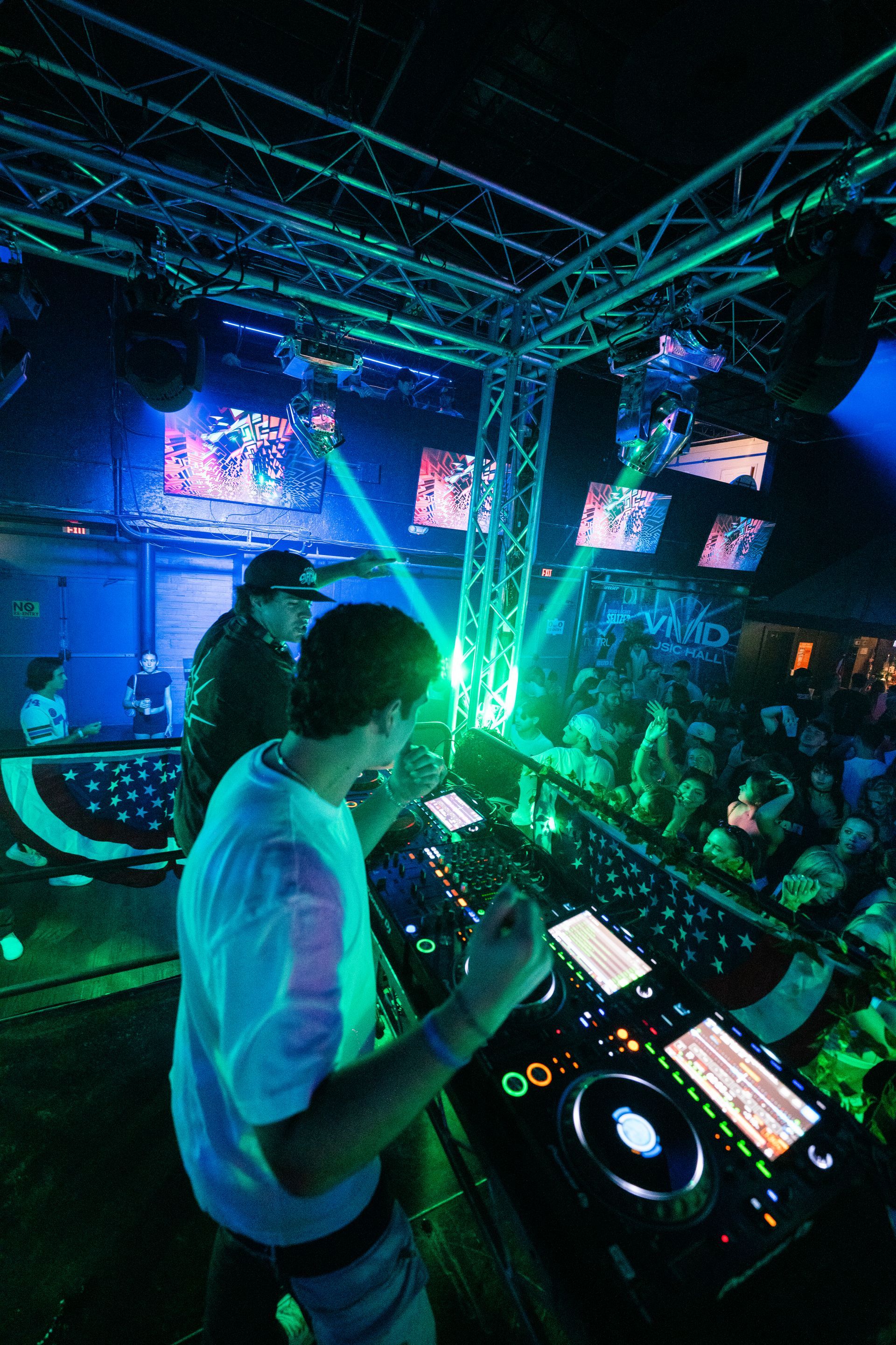 A dj is playing music in front of a crowd in a club.