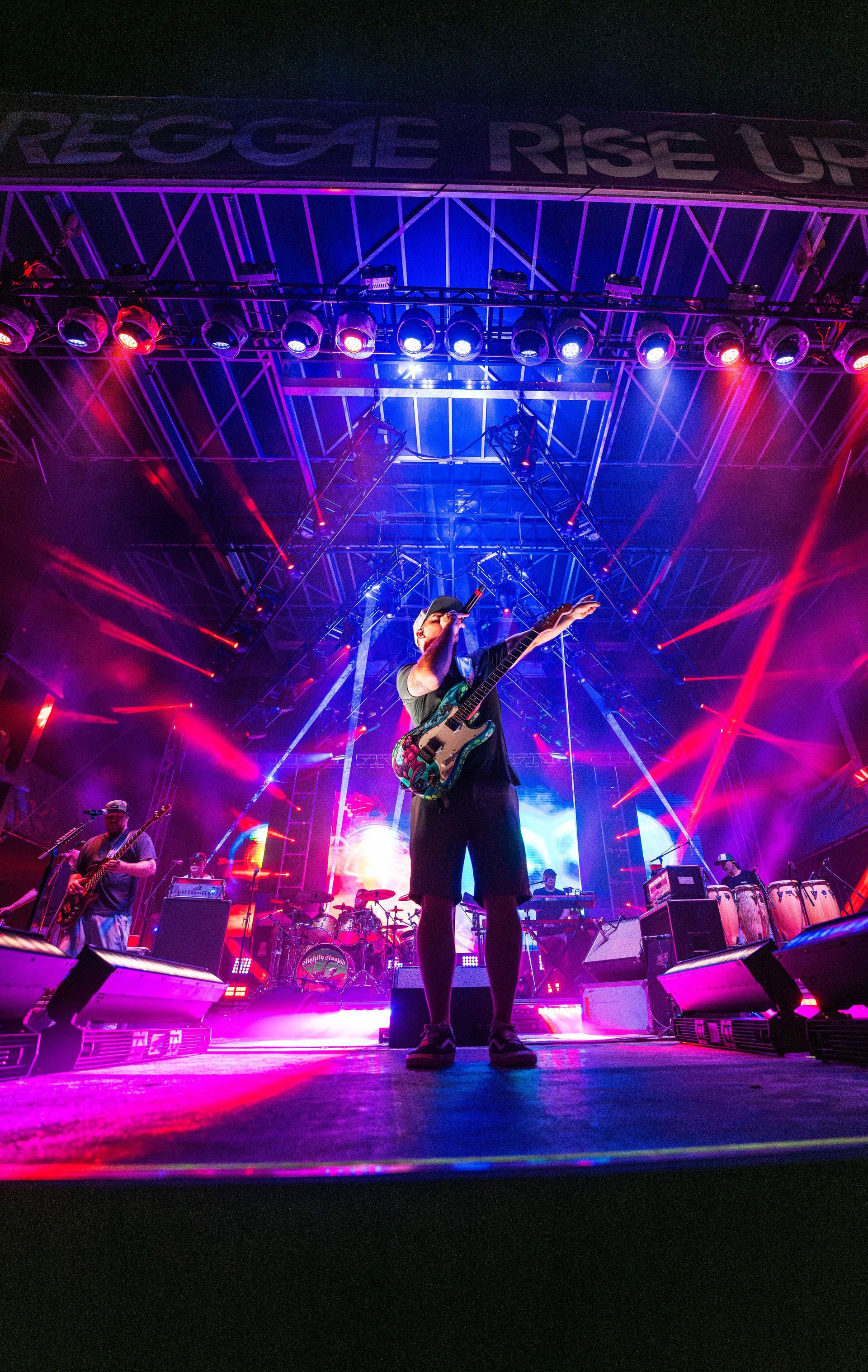 A man is playing a guitar on a stage with purple lights
