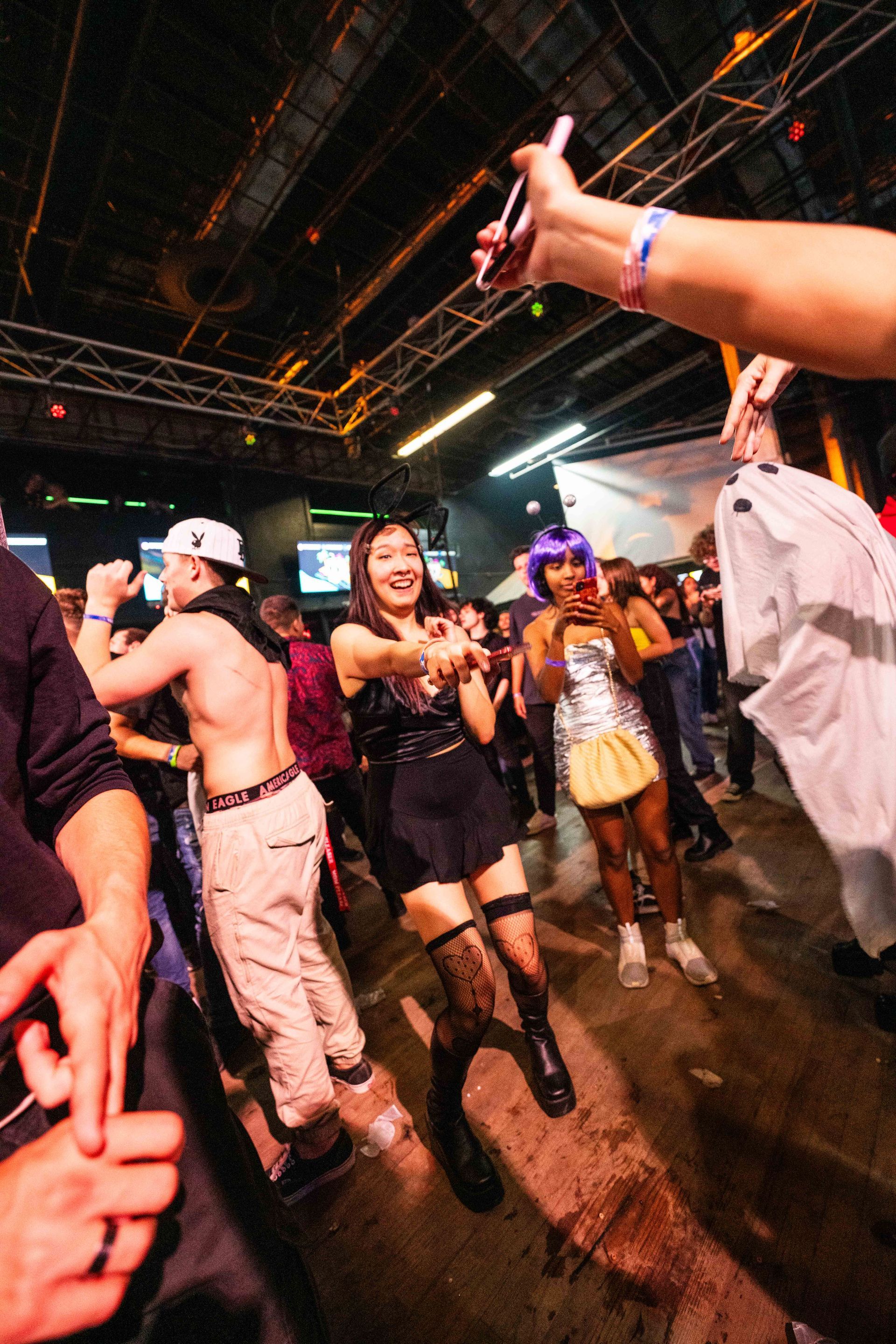 A group of people are dancing in a dark room at a party.
