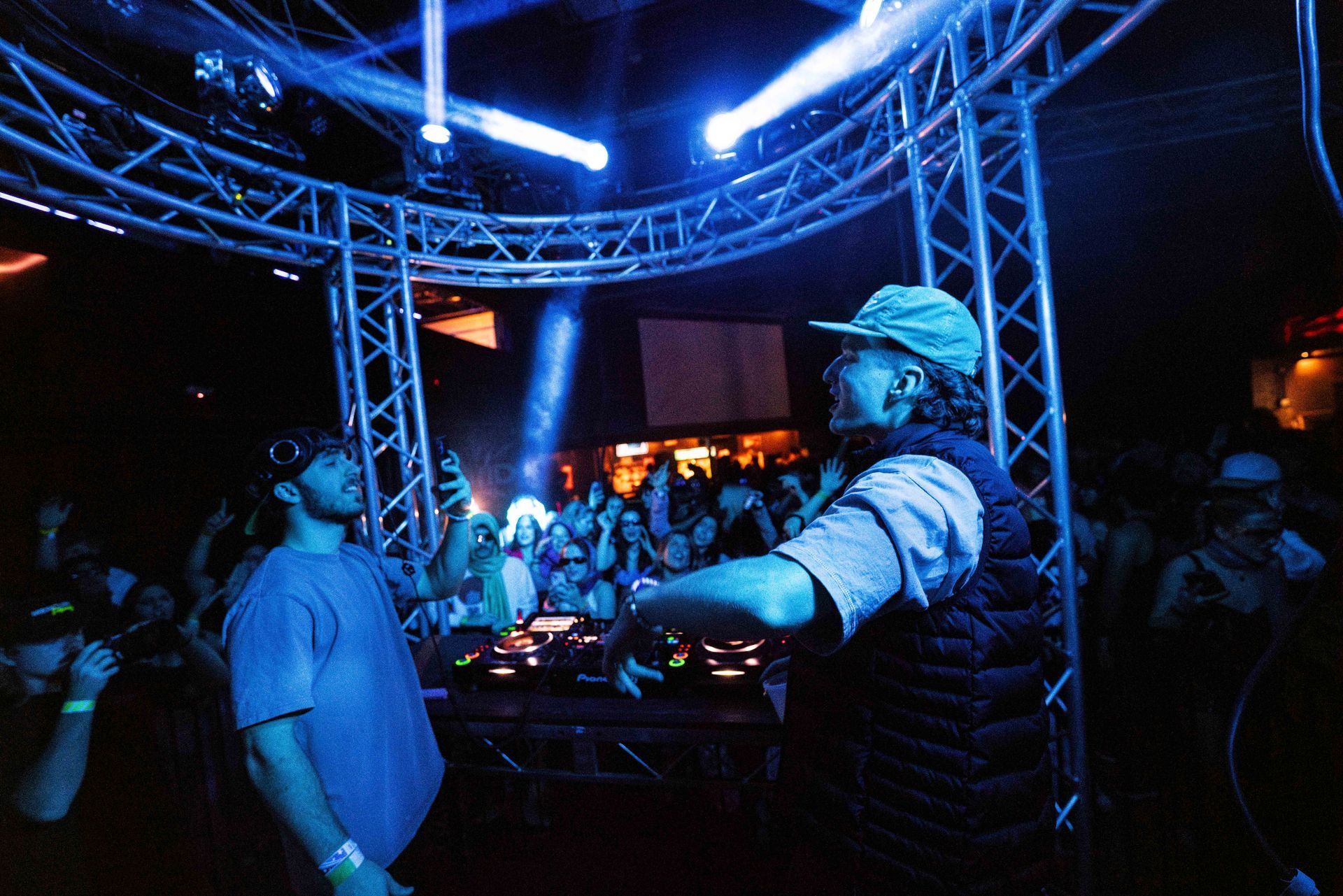 Two men are playing music in front of a crowd in a dark room