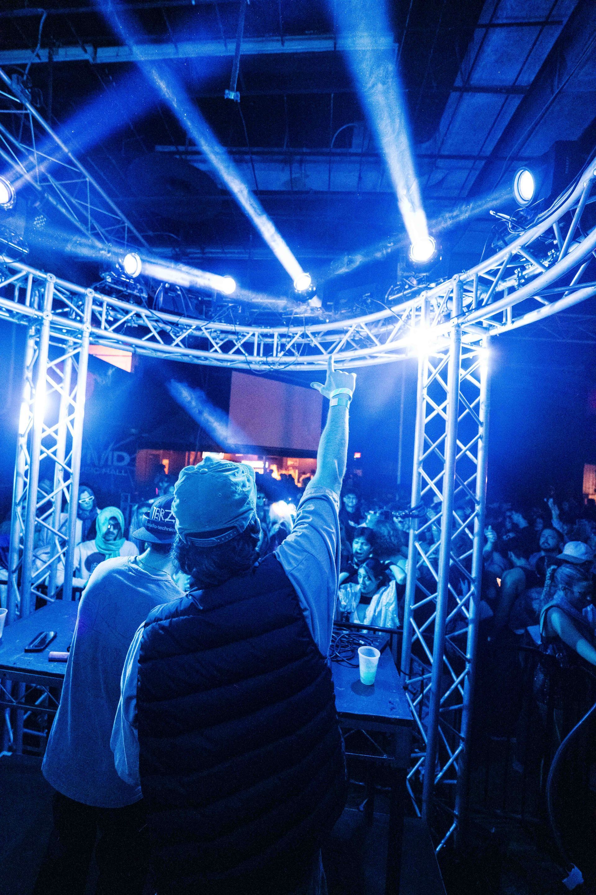 A man stands in front of a crowd at a concert with his arms in the air
