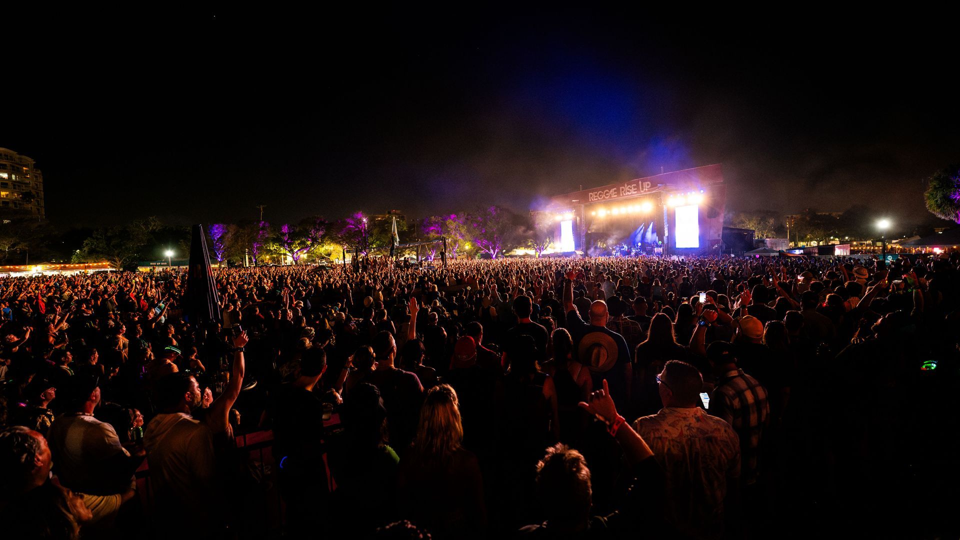 A large crowd of people are standing in front of a stage at a concert.