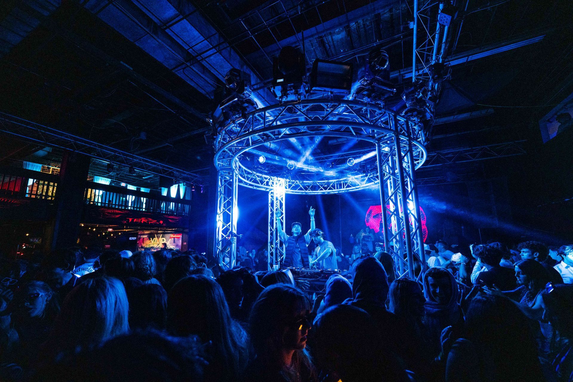 A crowd of people are gathered around a stage in a dark room