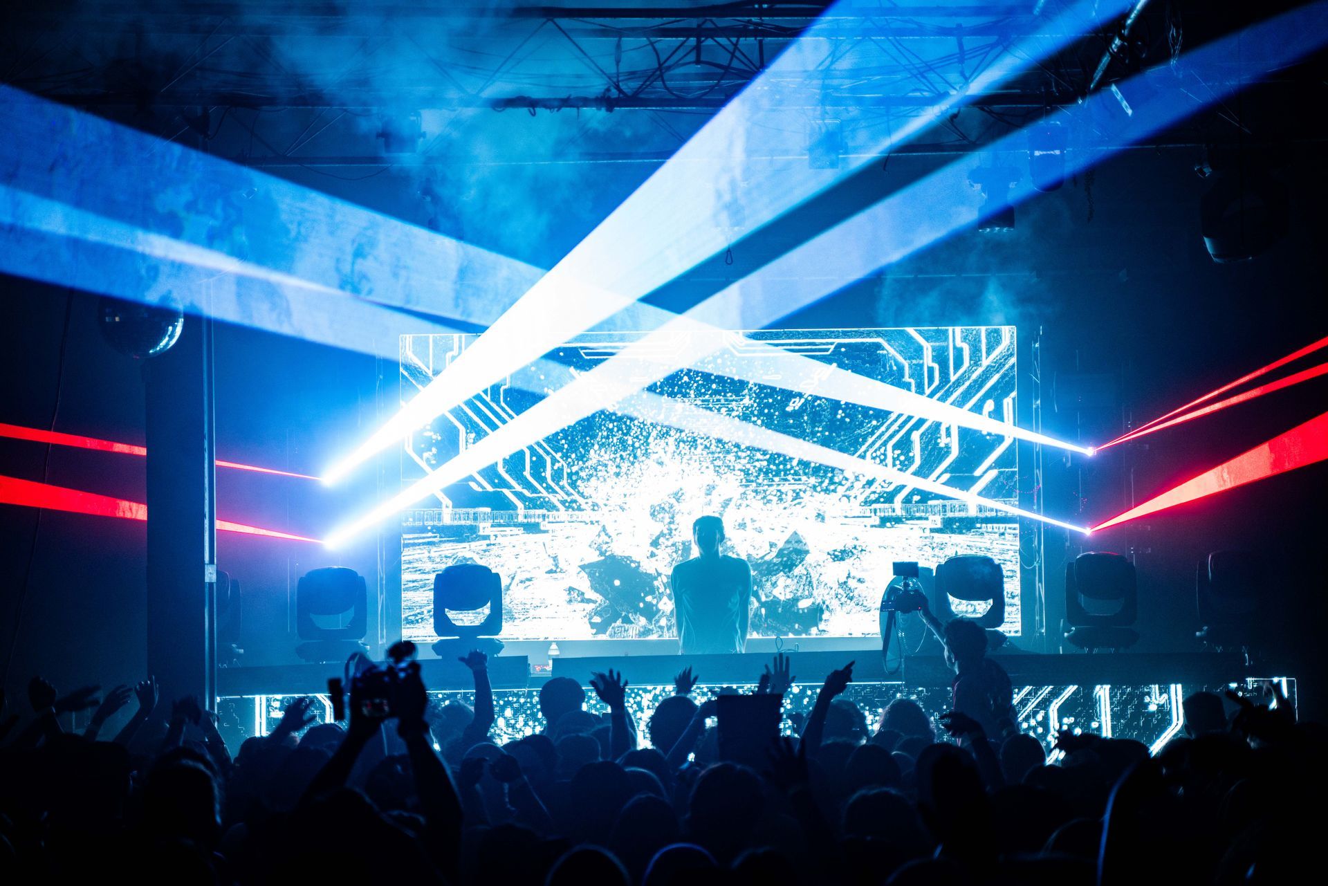 A crowd of people are watching a dj perform at a concert.