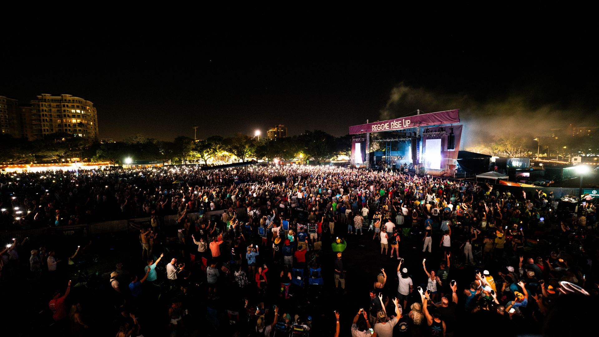 A large crowd of people are standing in front of a stage at a concert.