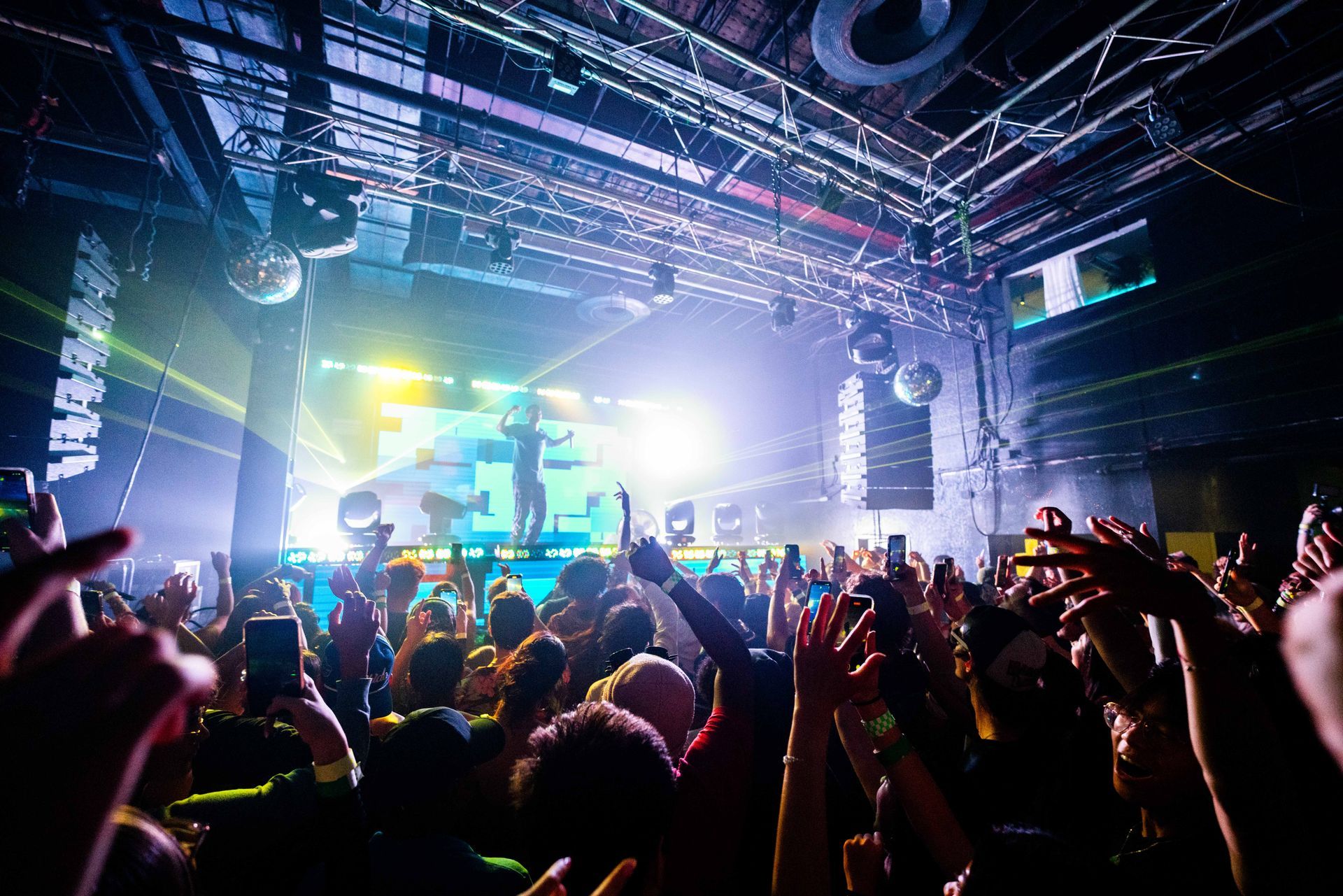 A crowd of people are standing in front of a stage at a concert.