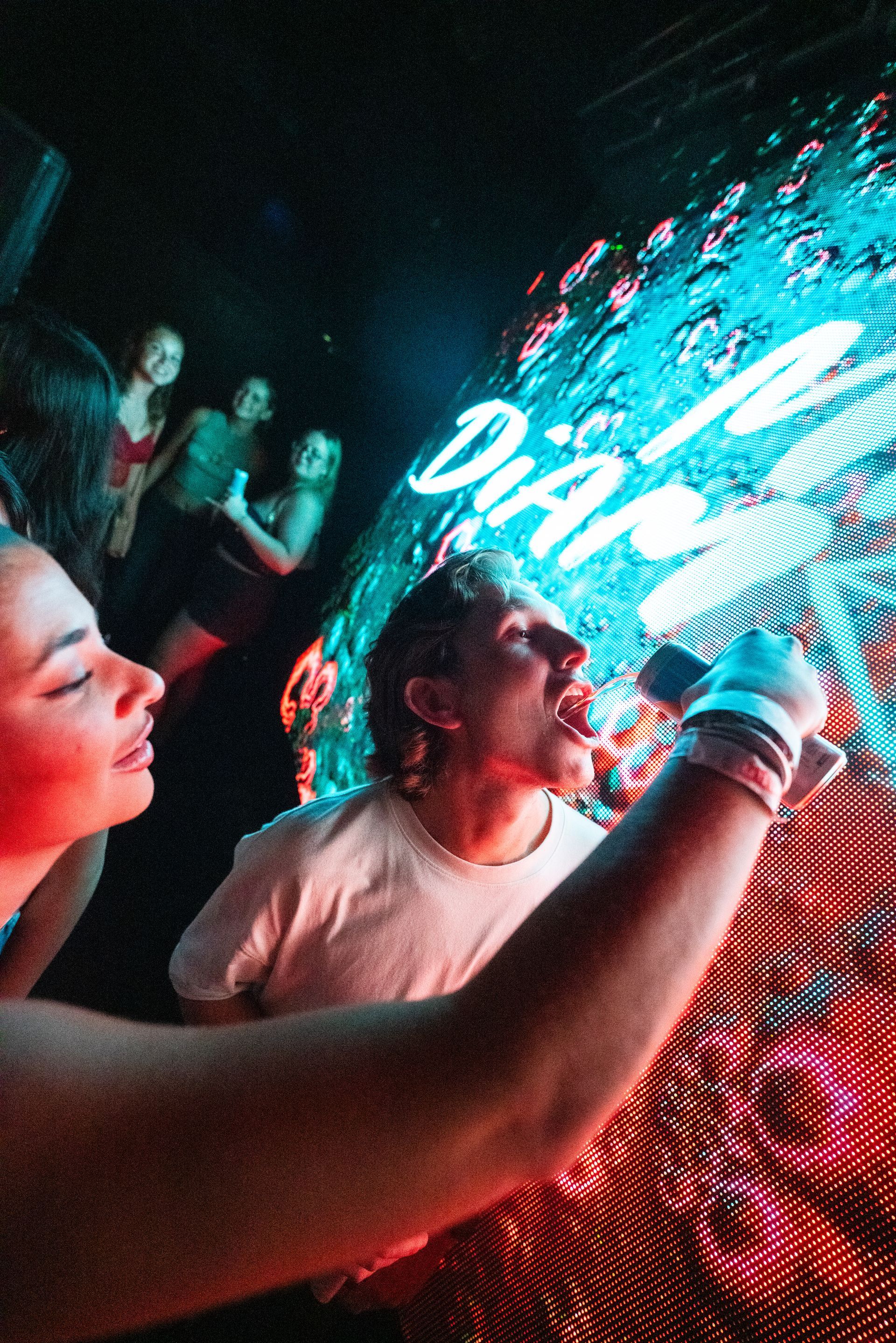 A man is singing into a microphone while a woman looks on