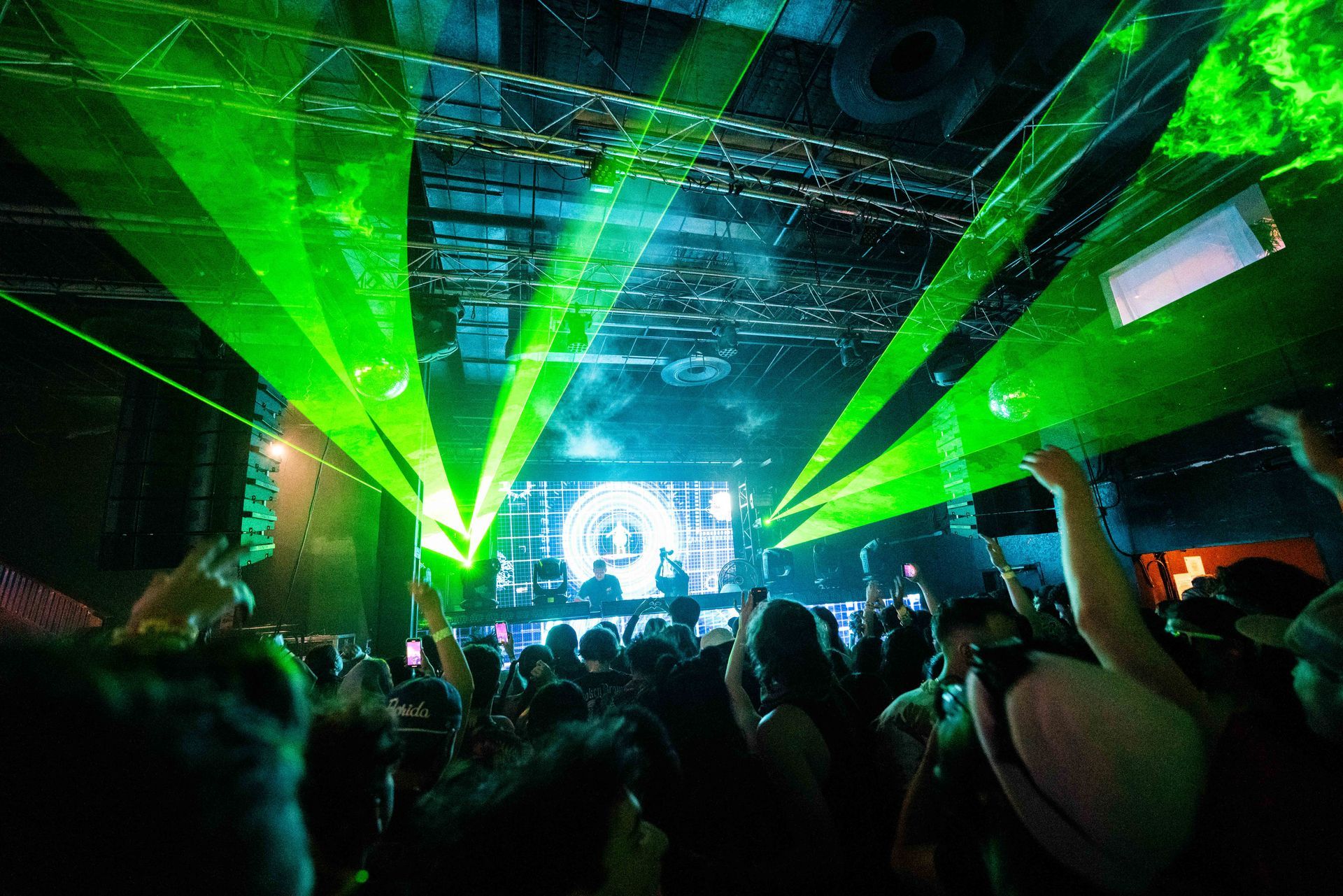 A crowd of people at a concert with green lights coming from the ceiling