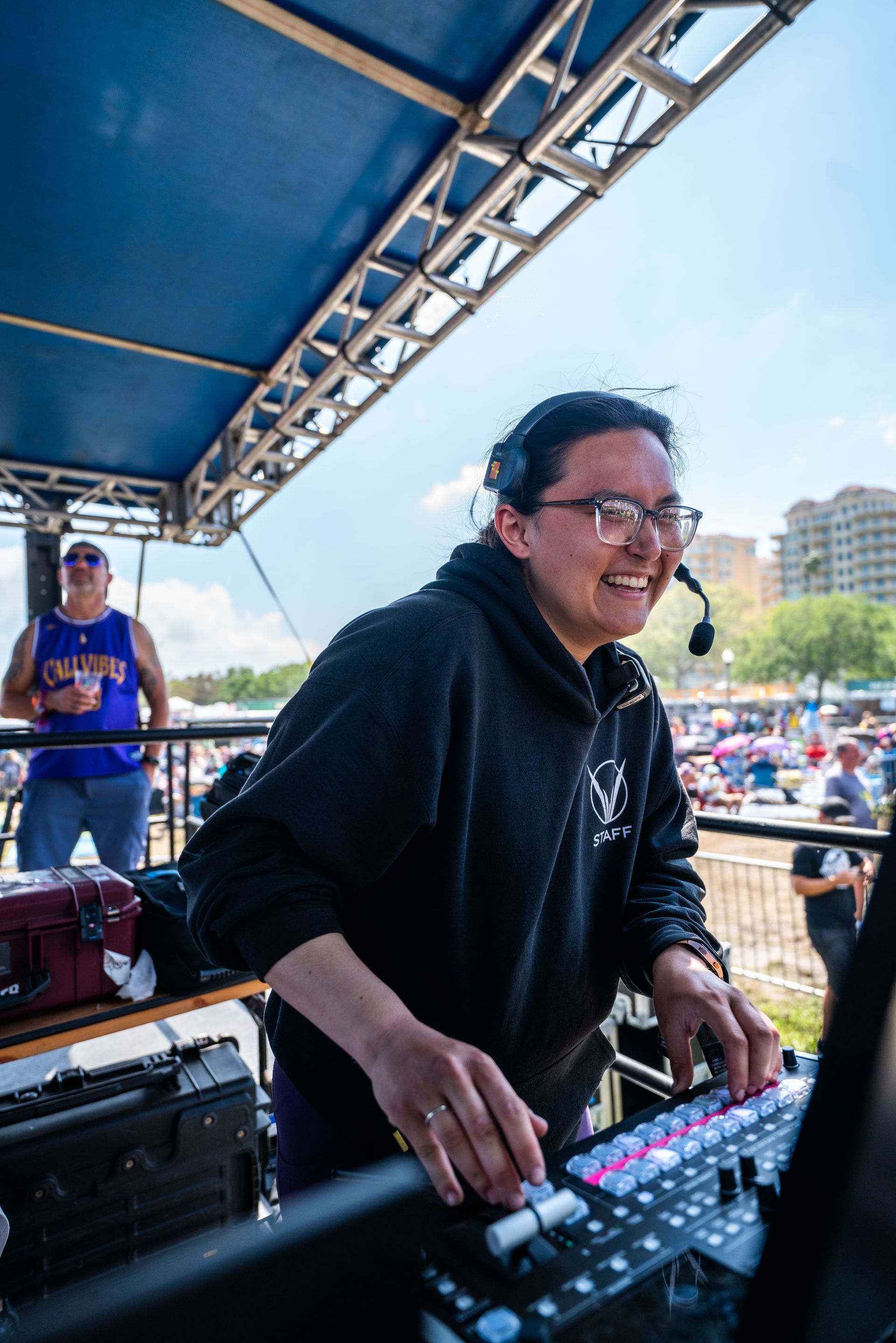 A man wearing headphones is playing music on a mixer.
