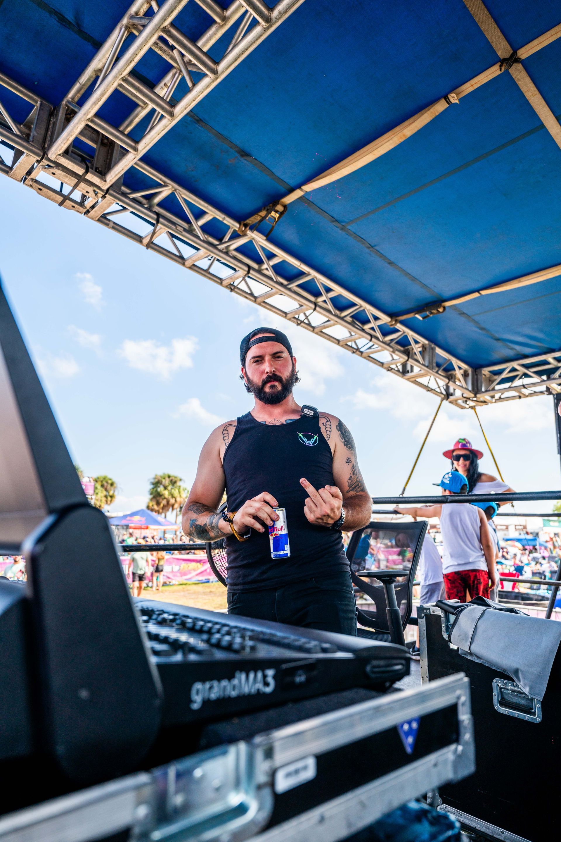 A man is standing under a blue canopy holding a red bull.