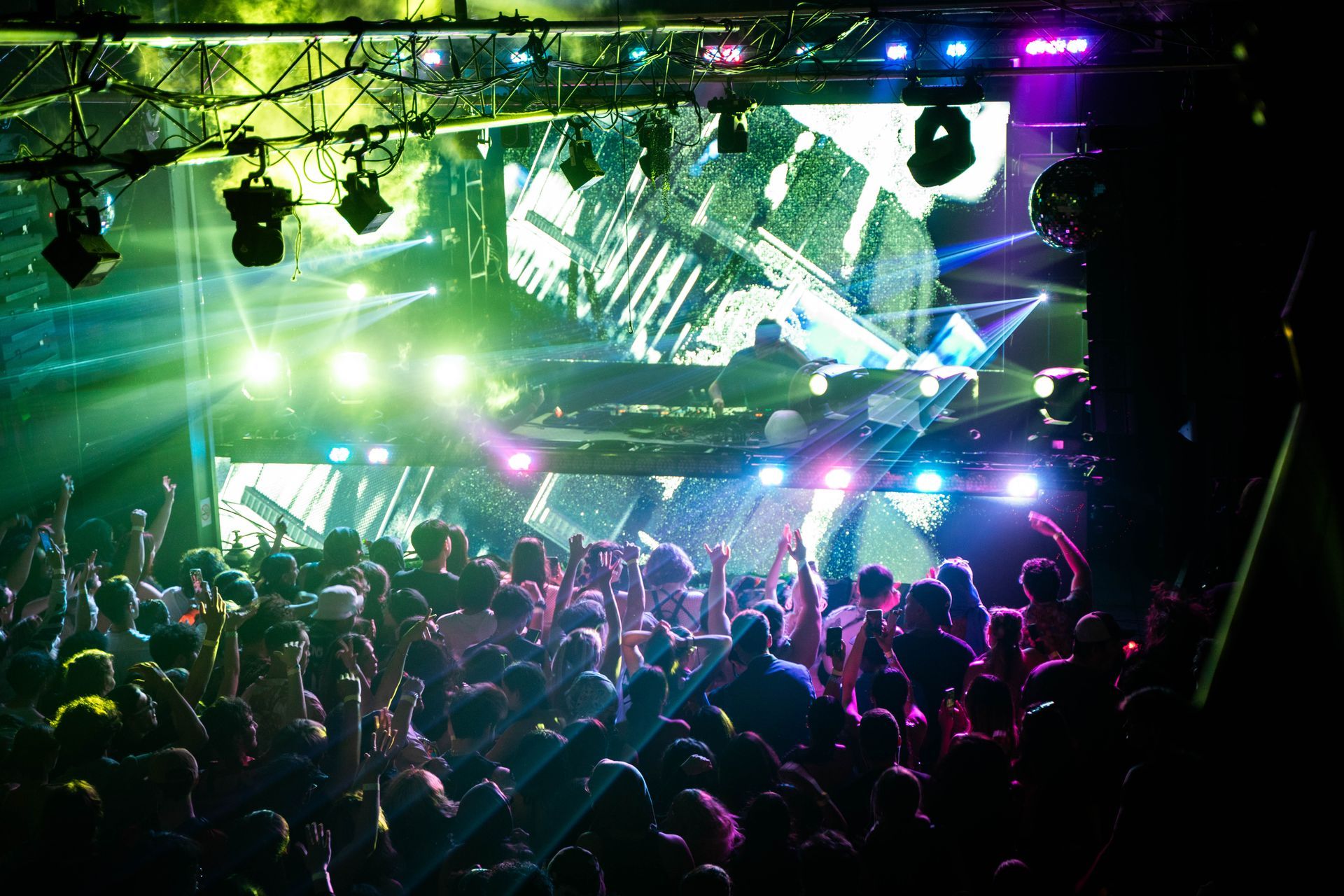 A crowd of people at a concert with their hands in the air