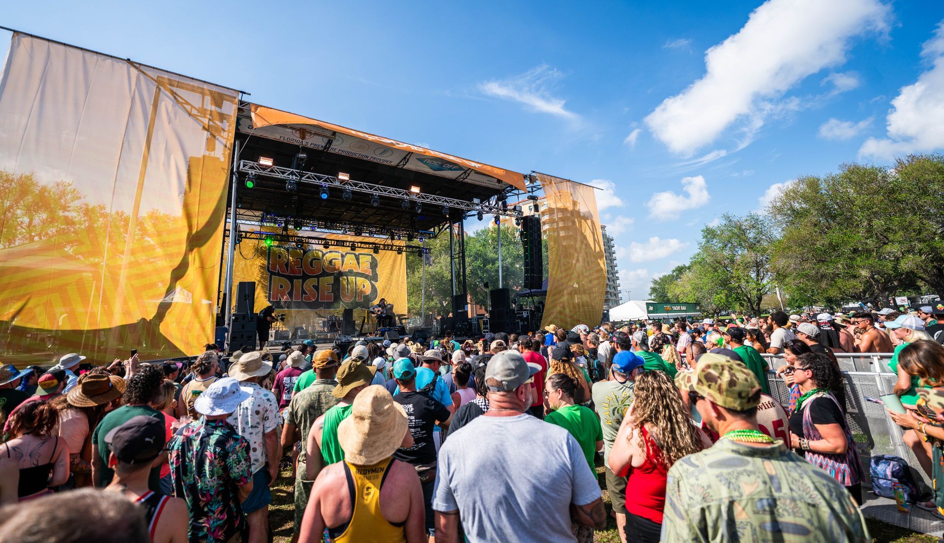 A crowd of people are standing in front of a stage at a music festival.